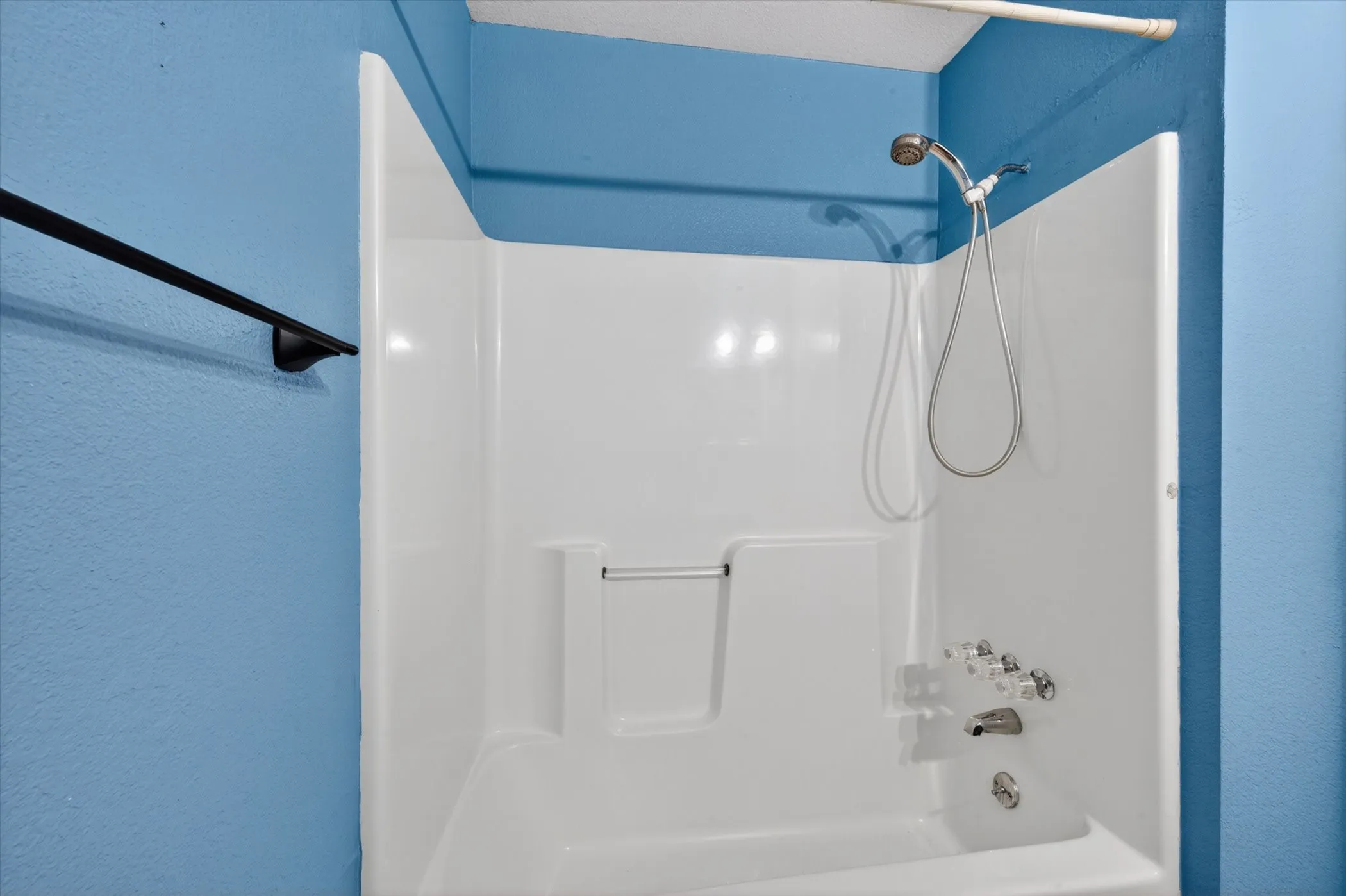 Tub and shower combination unit featuring a handheld showerhead, integrated soap dish, and clear acrylic faucet handles