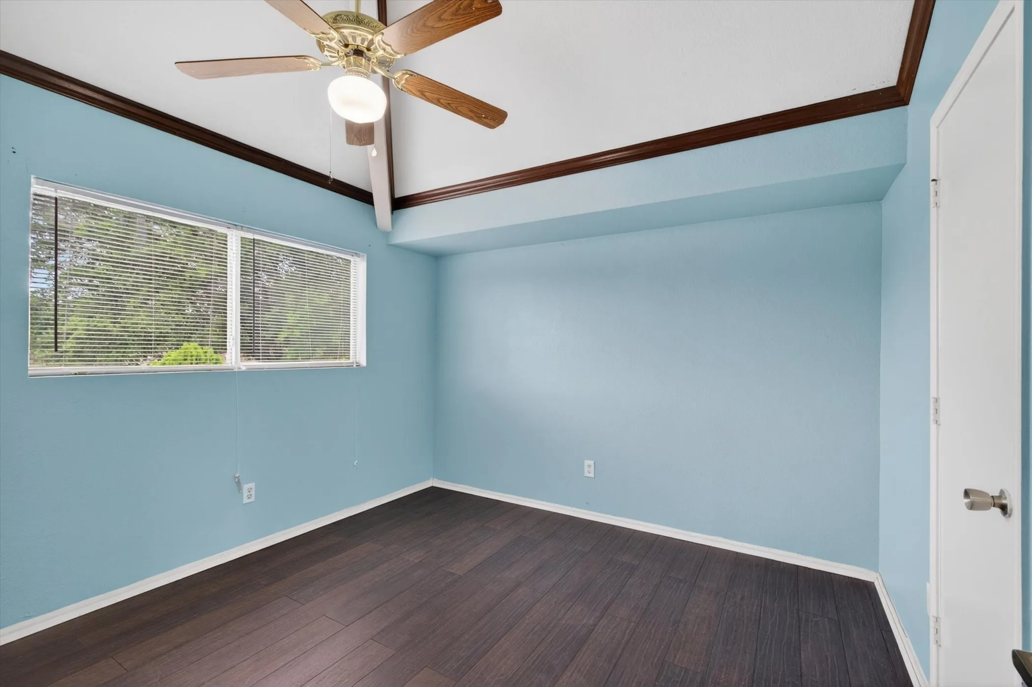 Vaulted ceiling with wood-finish beams and a ceiling fan light fixture