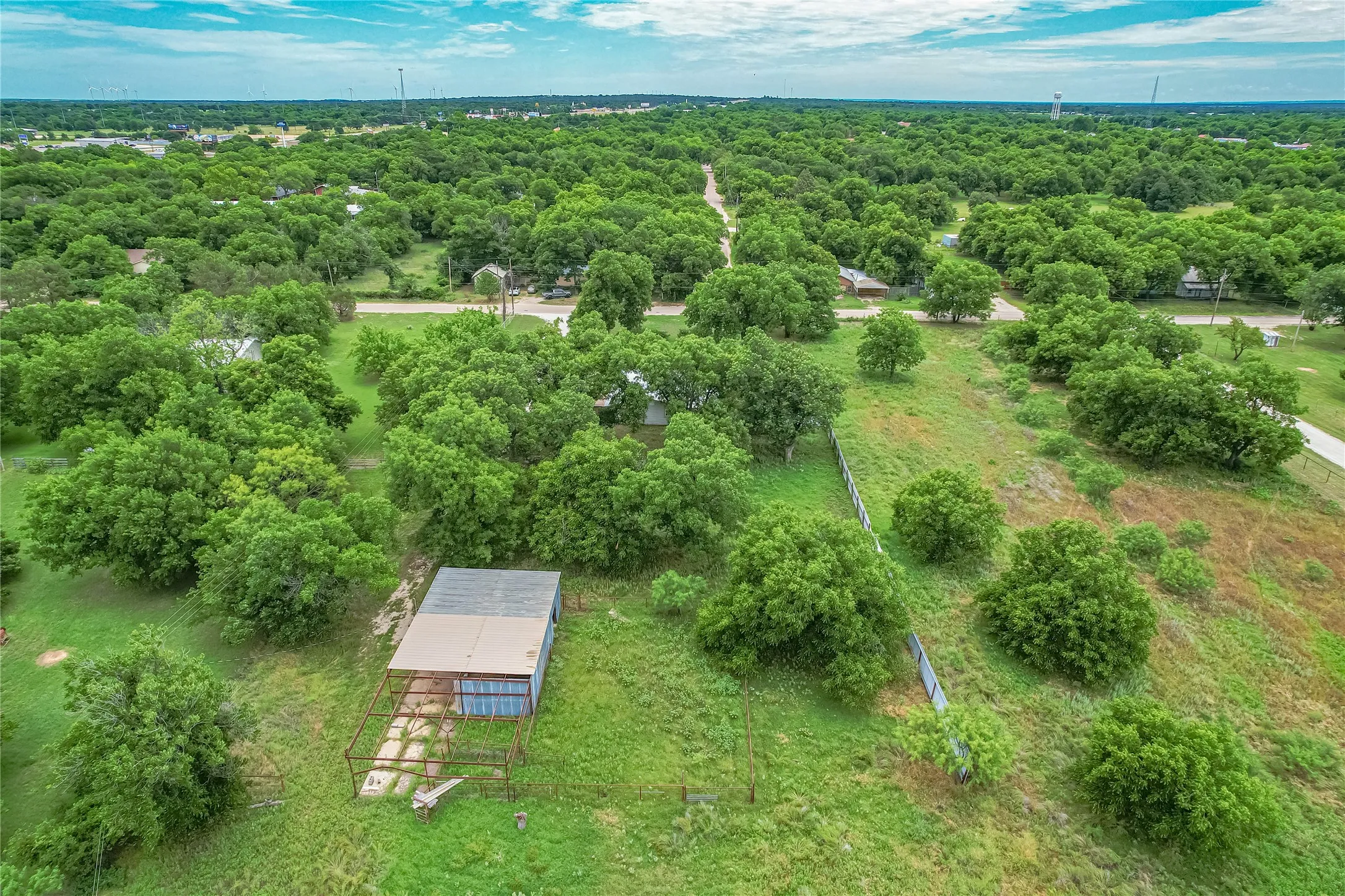 Expansive land parcel featuring a metal-roofed outbuilding with a fenced enclosure