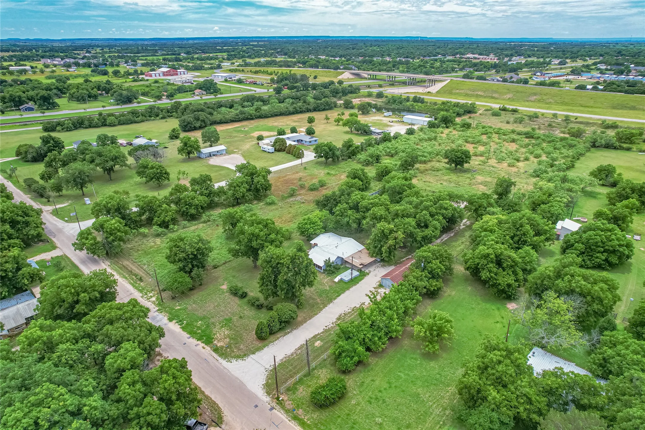 Expansive land parcel featuring multiple structures amidst mature trees and open green spaces