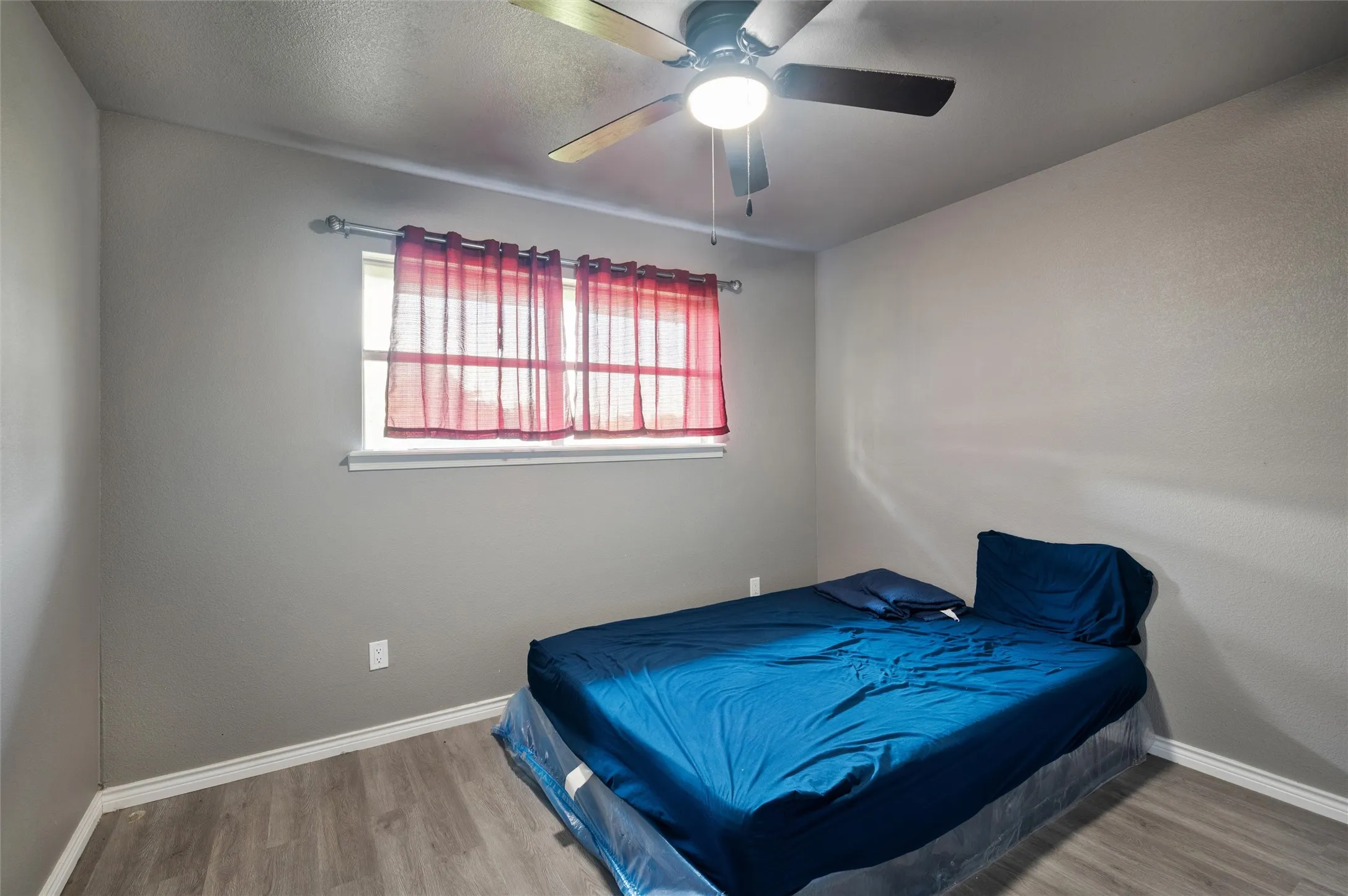 Interior space featuring wood-finish flooring, a ceiling fan with integrated lighting, and neutral wall paint