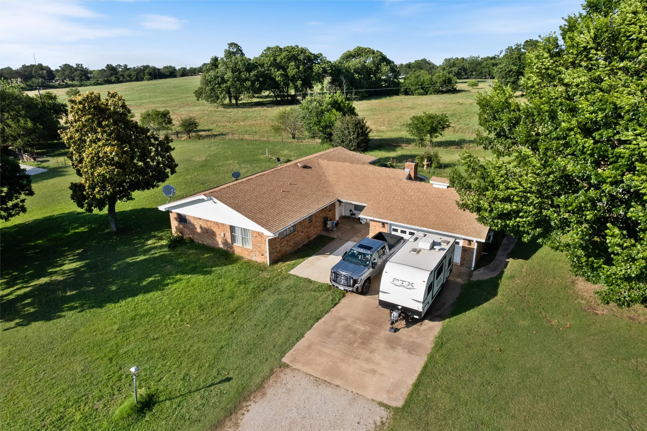 Single-story brick residence featuring a brown shingle roof and a concrete driveway