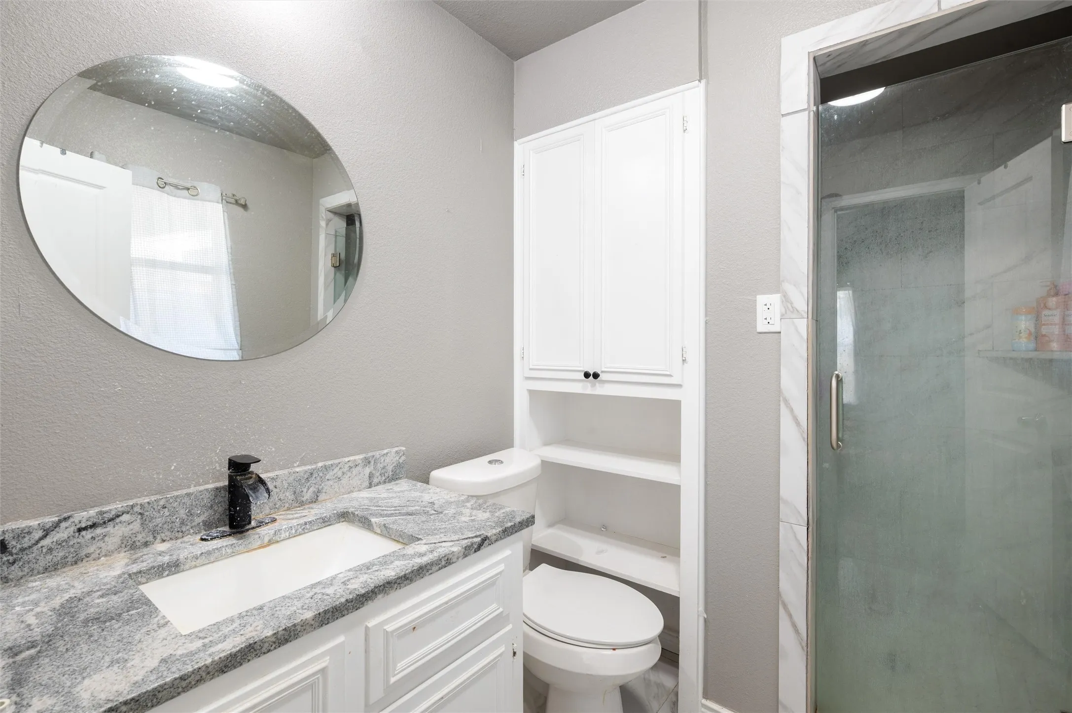 Bathroom featuring a vanity with an integrated sink, a dark-toned faucet, and a patterned countertop