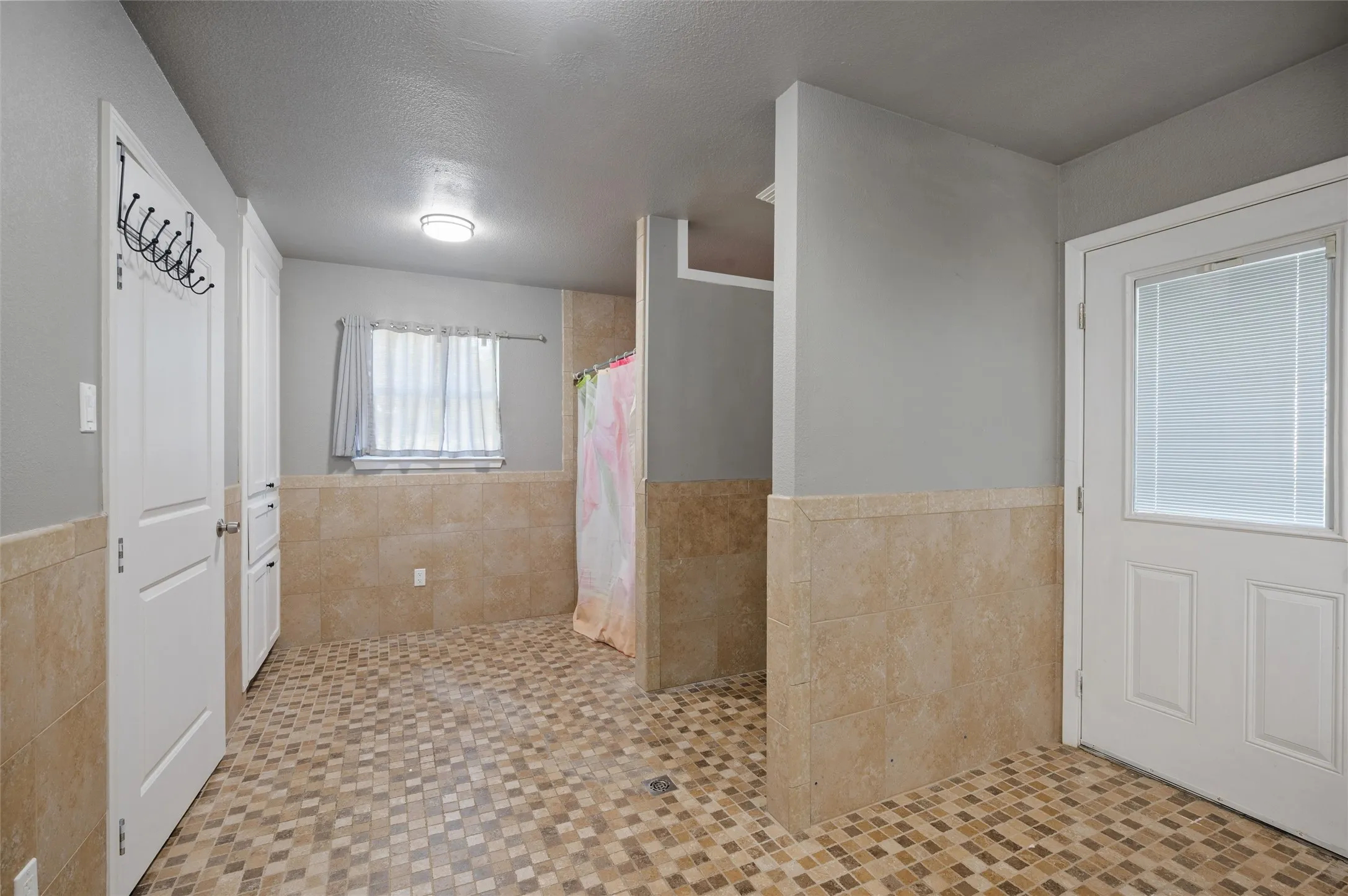 Tile flooring with a diamond pattern, light gray walls, and lower wall tiling