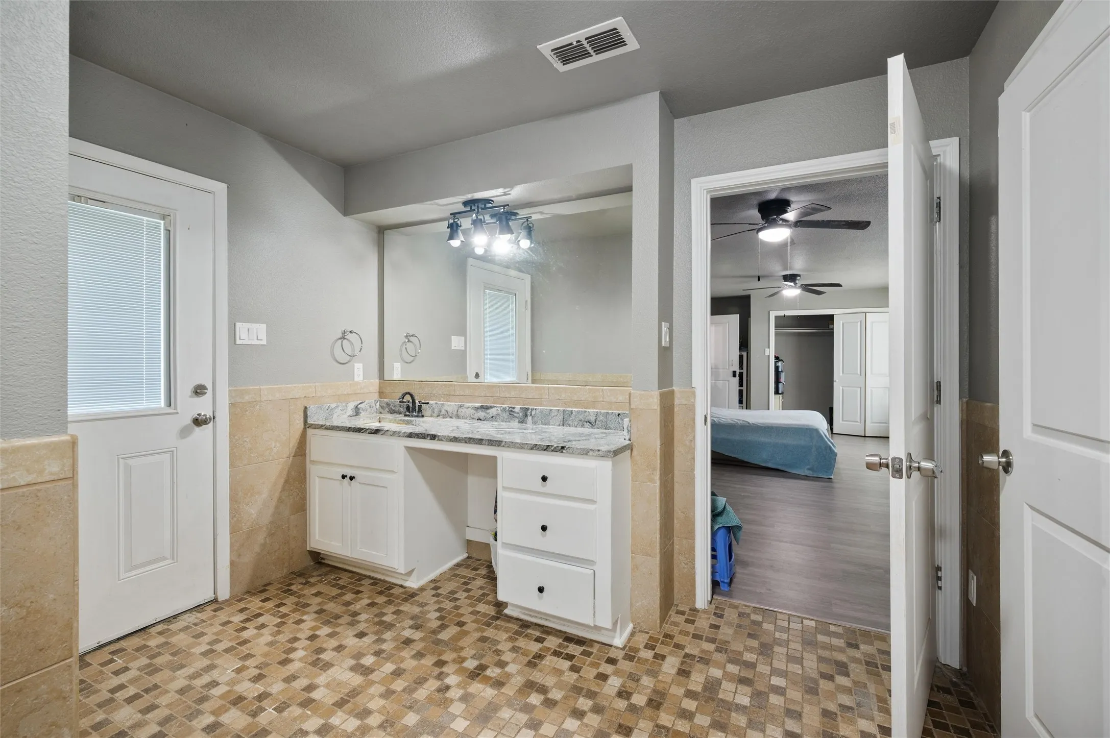 Bathroom vanity featuring a single sink, light-toned countertop, and white cabinetry