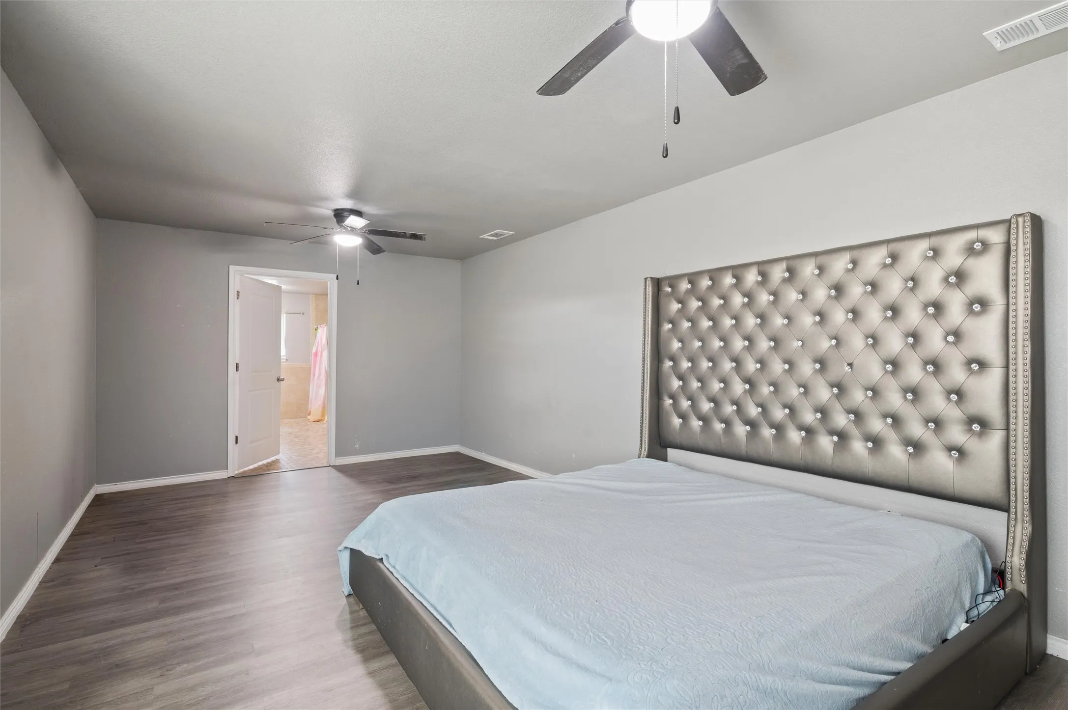 Spacious room featuring wood-finish flooring, two ceiling fans with lighting, and light gray wall paint