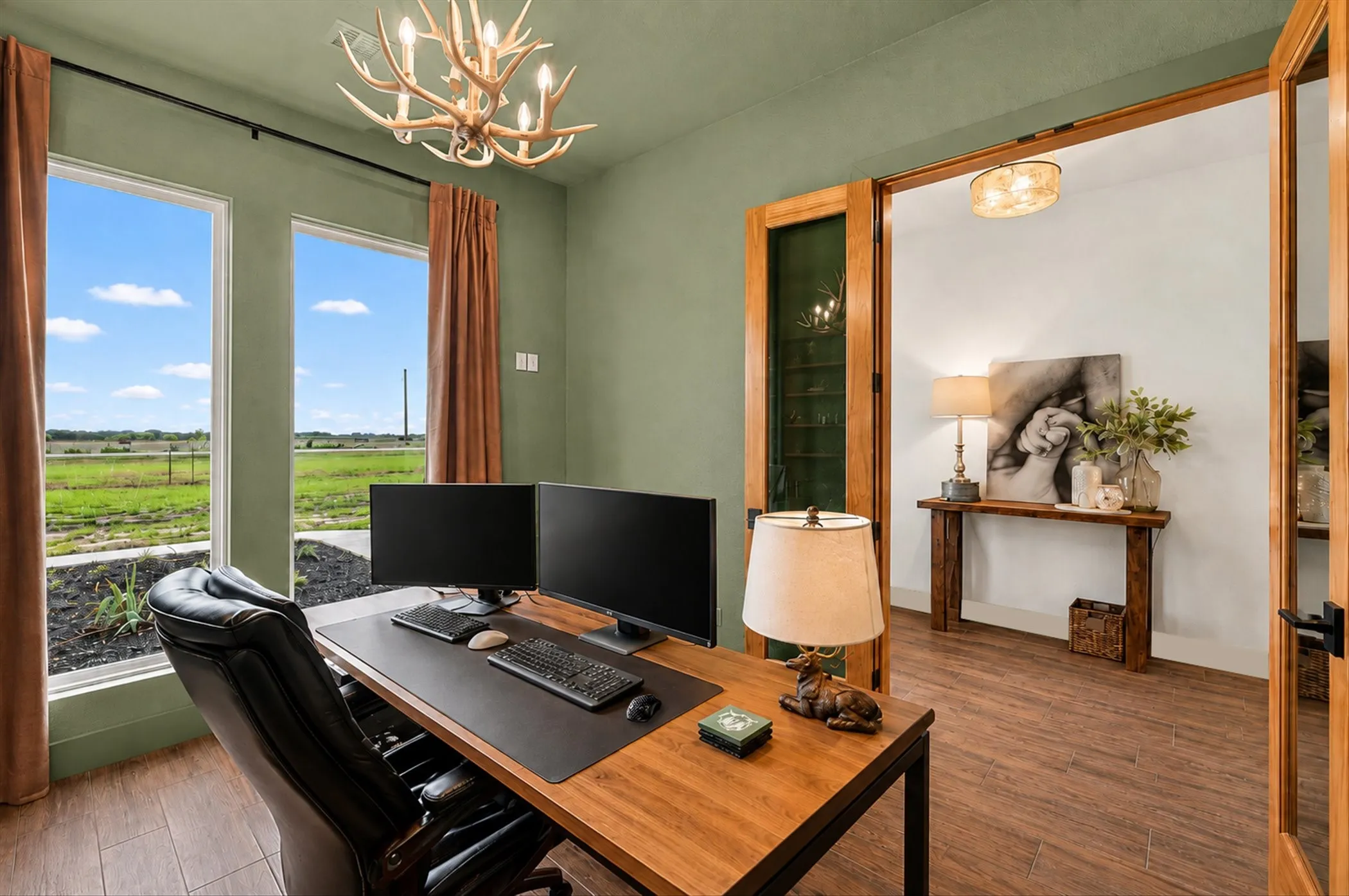 Room featuring two large windows, wood-look tile flooring, a decorative antler-style chandelier, and double French doors with glass panels
