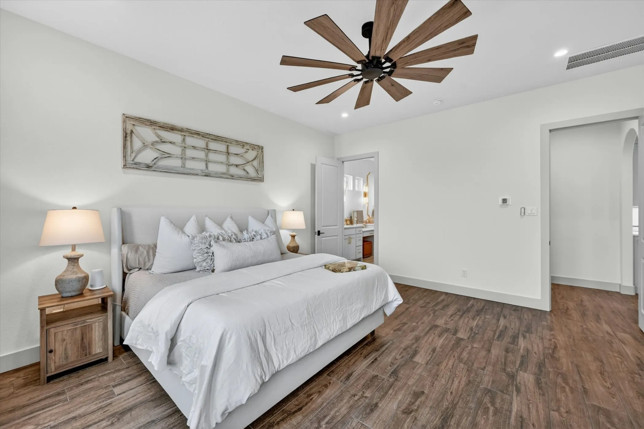 Spacious interior room featuring wood-finish tile flooring, a contemporary ceiling fan with wooden blades, recessed lighting, and a neutral color palette