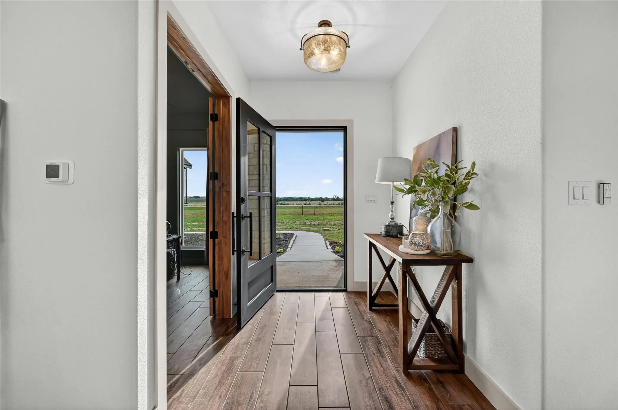 Entryway featuring wood-look tile flooring, a decorative glass flush-mount light fixture, and a black-framed glass-paneled door
