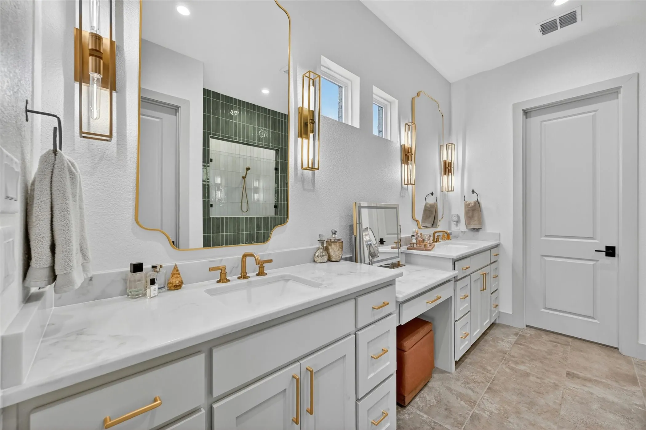 Dual vanity with light biege cabinetry, light stone-countertops, and gold-finish hardware