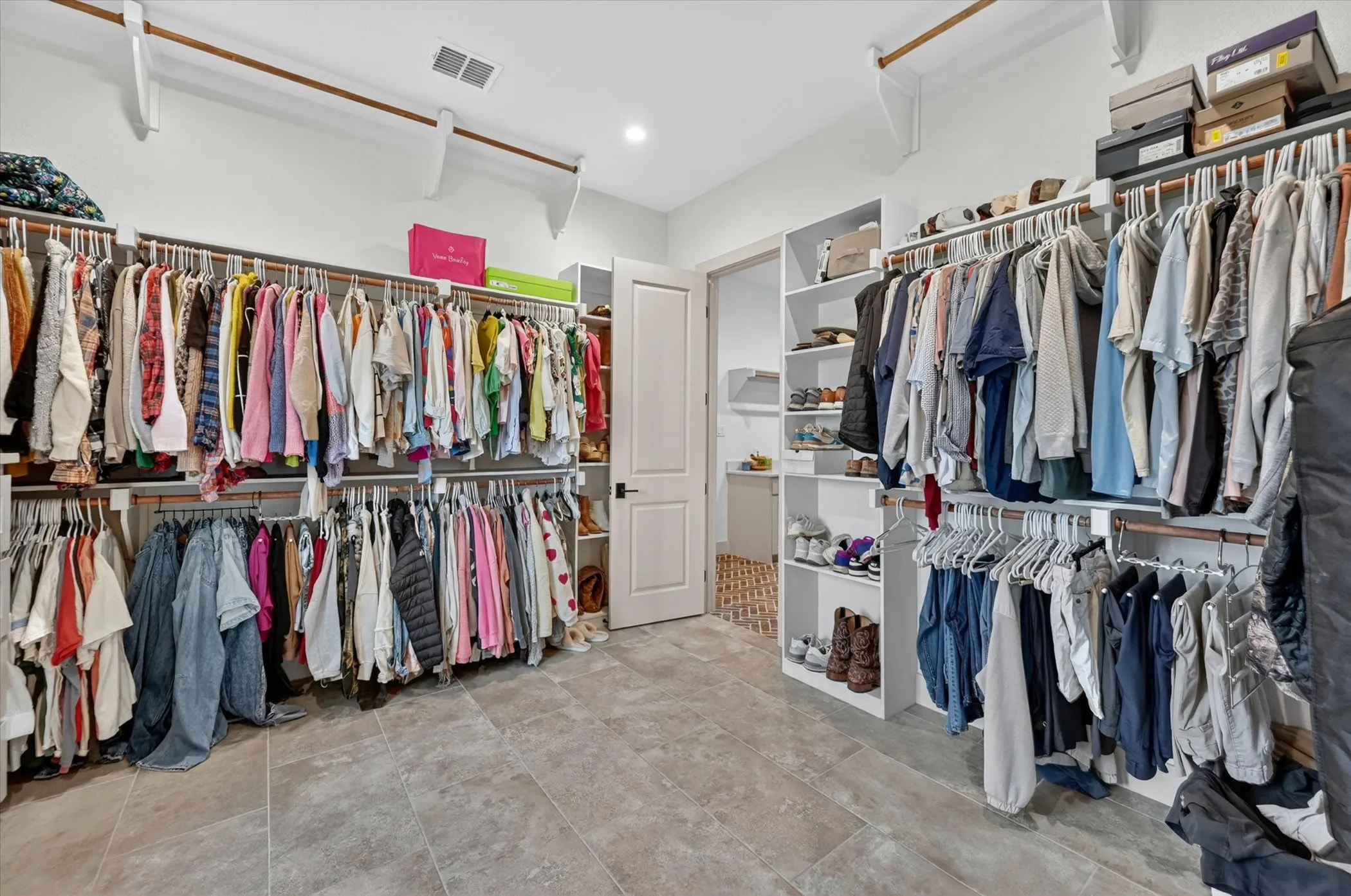 Expansive walk-in prinary closet with access to the laundry and mud room.