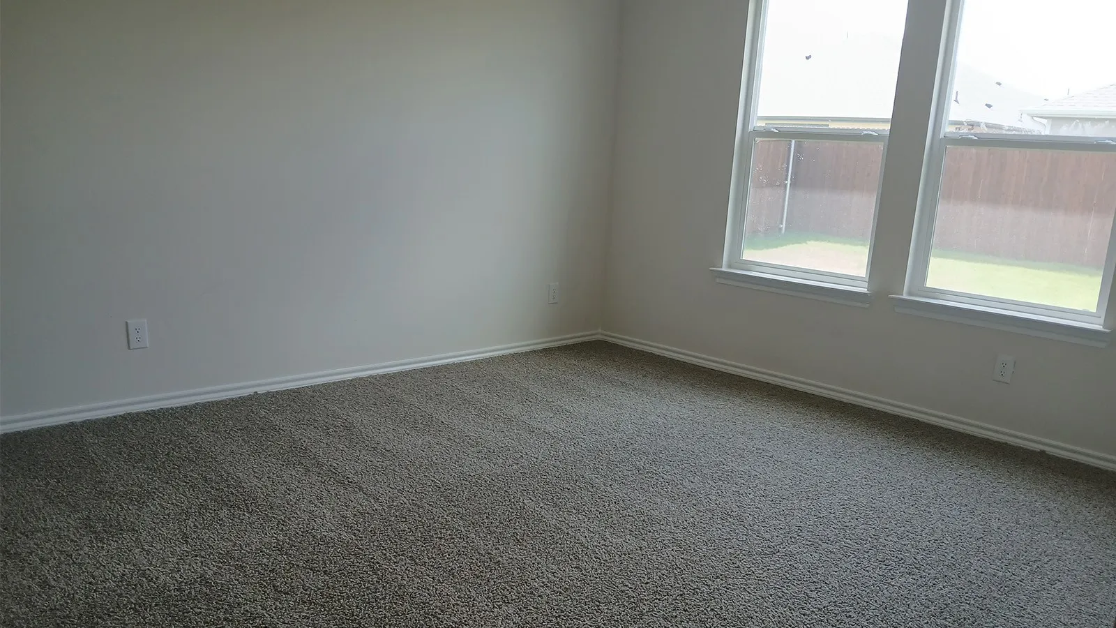 Neutral tone carpet flooring with white baseboards