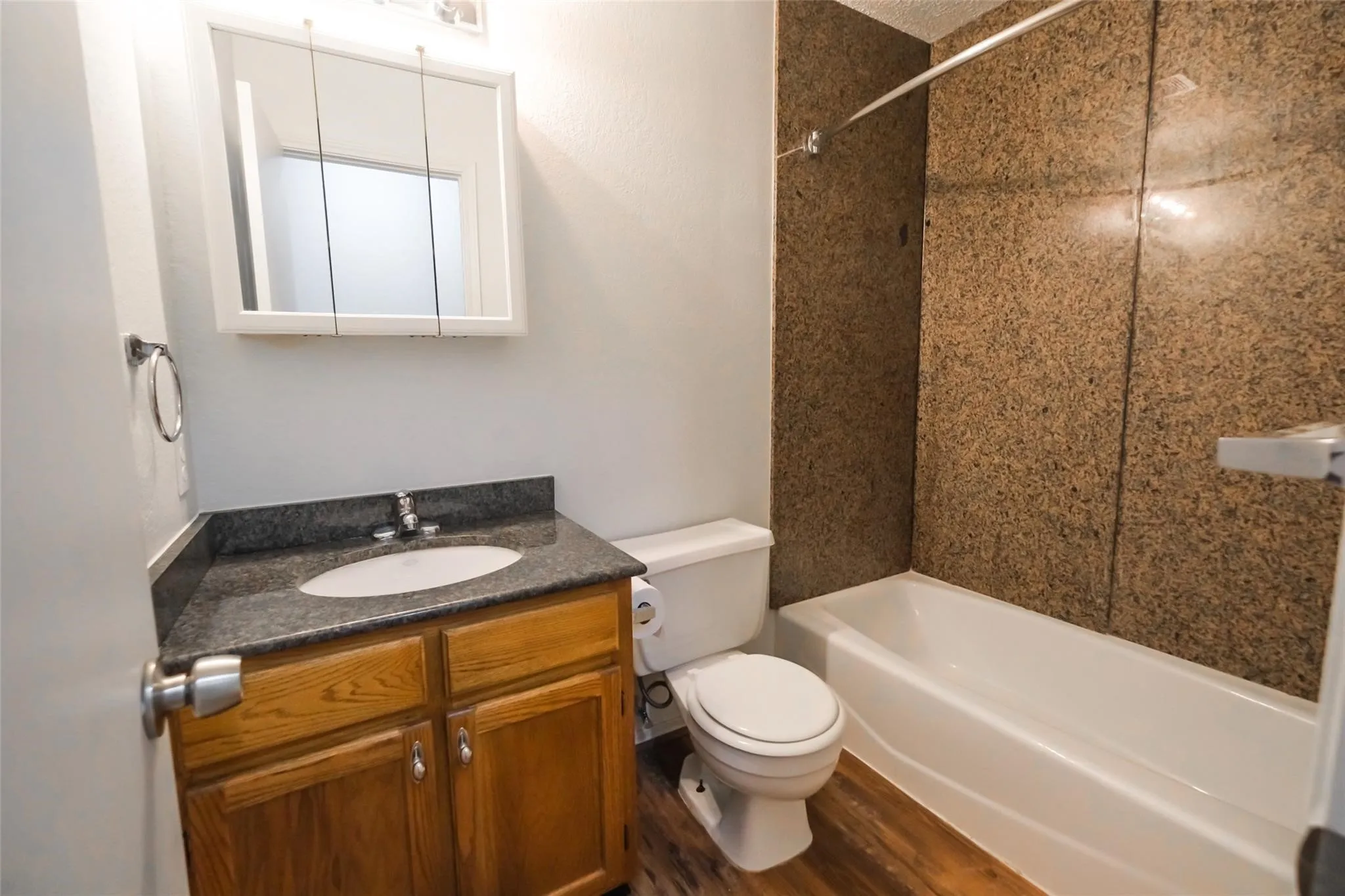 Bathroom featuring a white bathtub, wood-finish flooring, and a vanity with a dark countertop