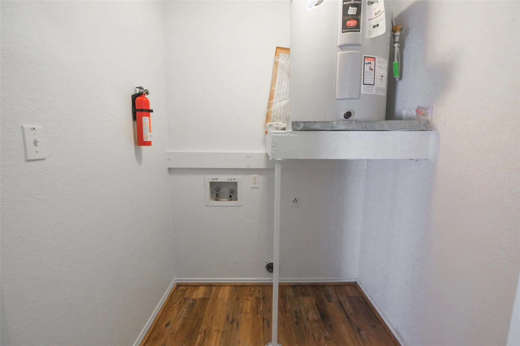 Utility space featuring a water heater, washer/dryer hookups, and wood-finish flooring