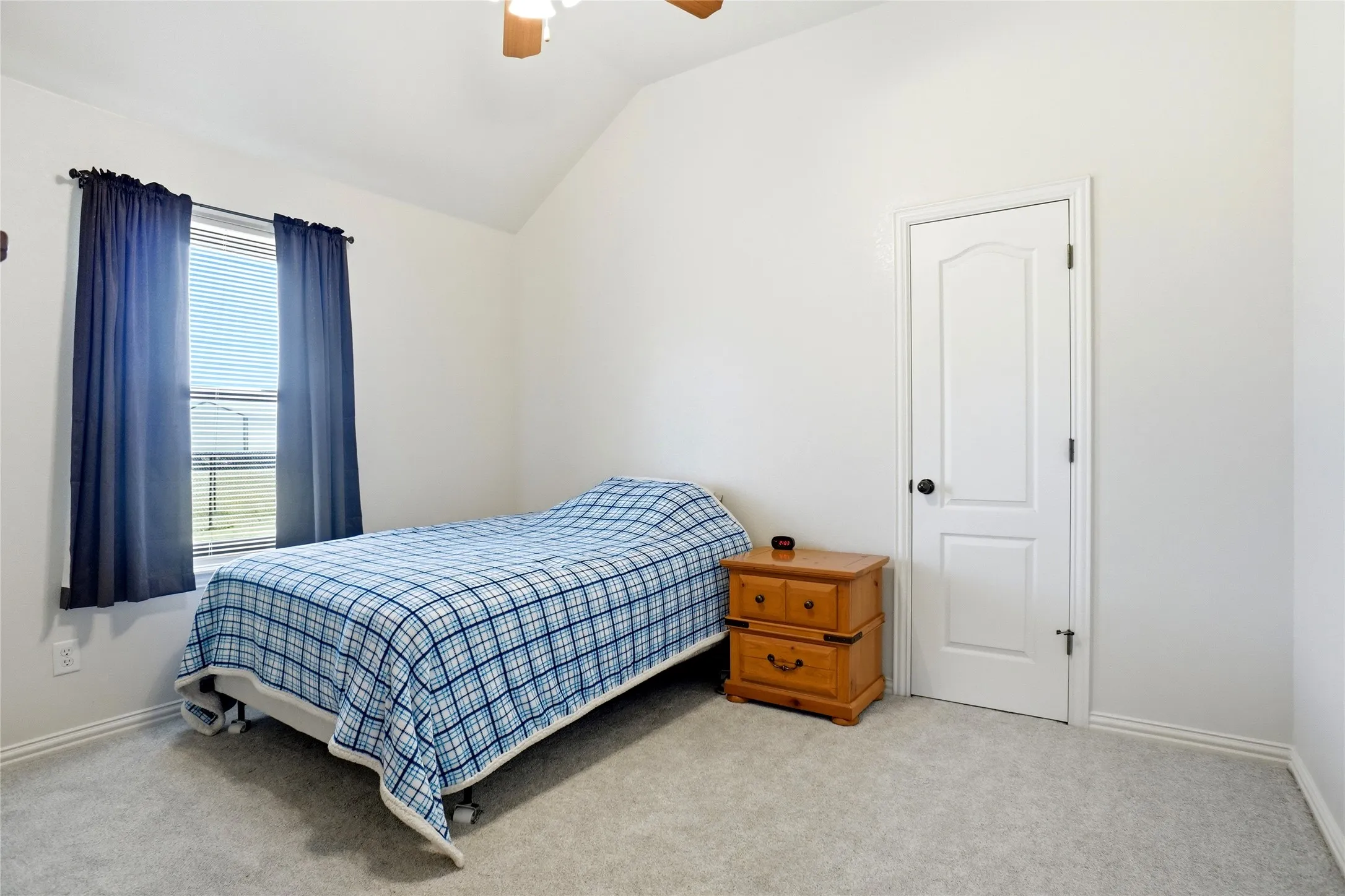 Carpeted room featuring a window with blinds, a white paneled door with black hardware, and a ceiling fan