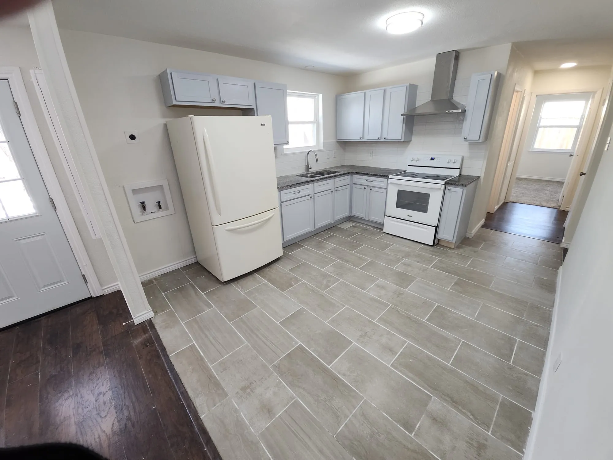Kitchen featuring light gray cabinetry, dark countertops, and a white subway tile backsplash