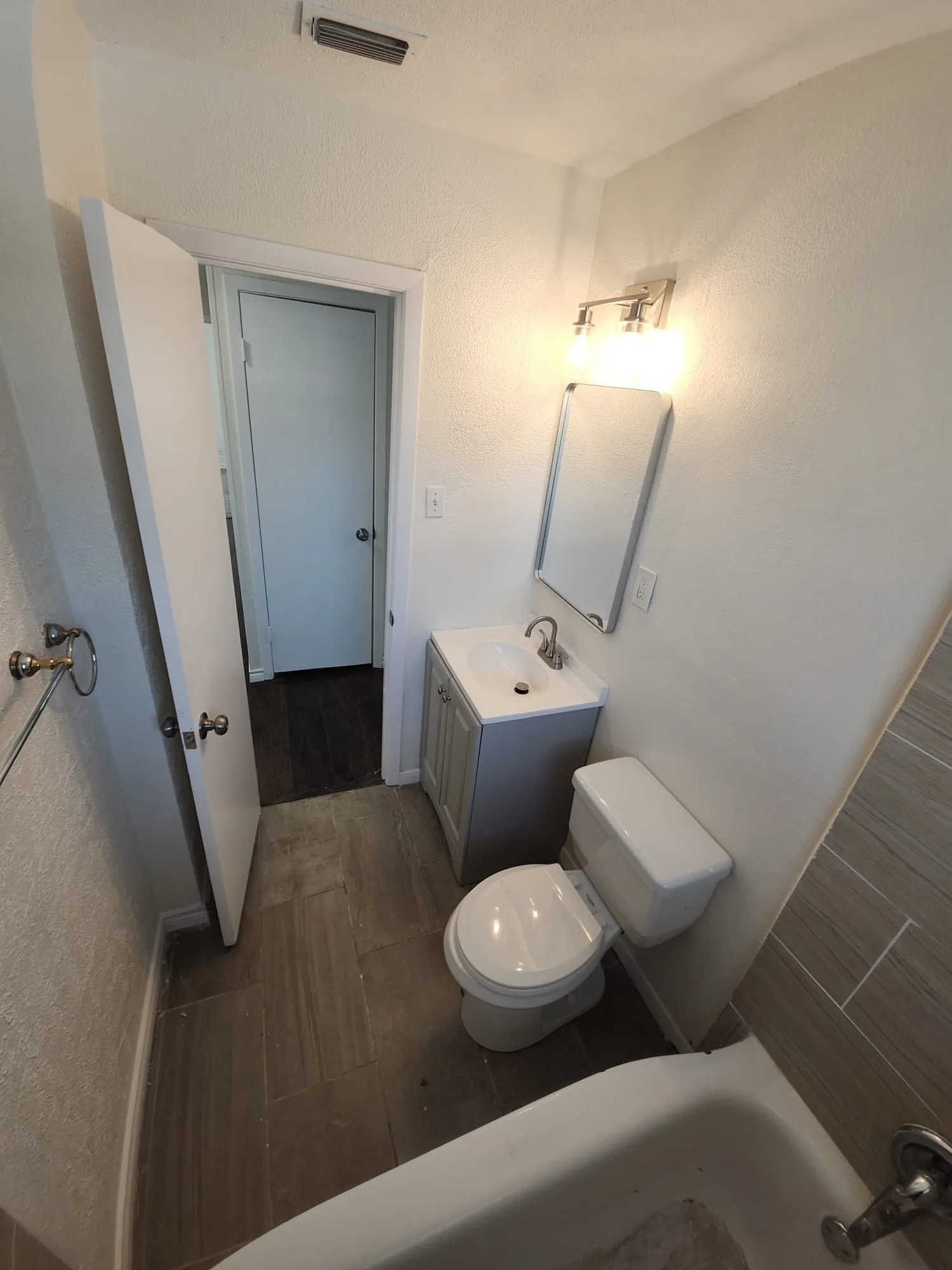 Bathroom featuring a white bathtub, a toilet, and a vanity with a rectangular sink
