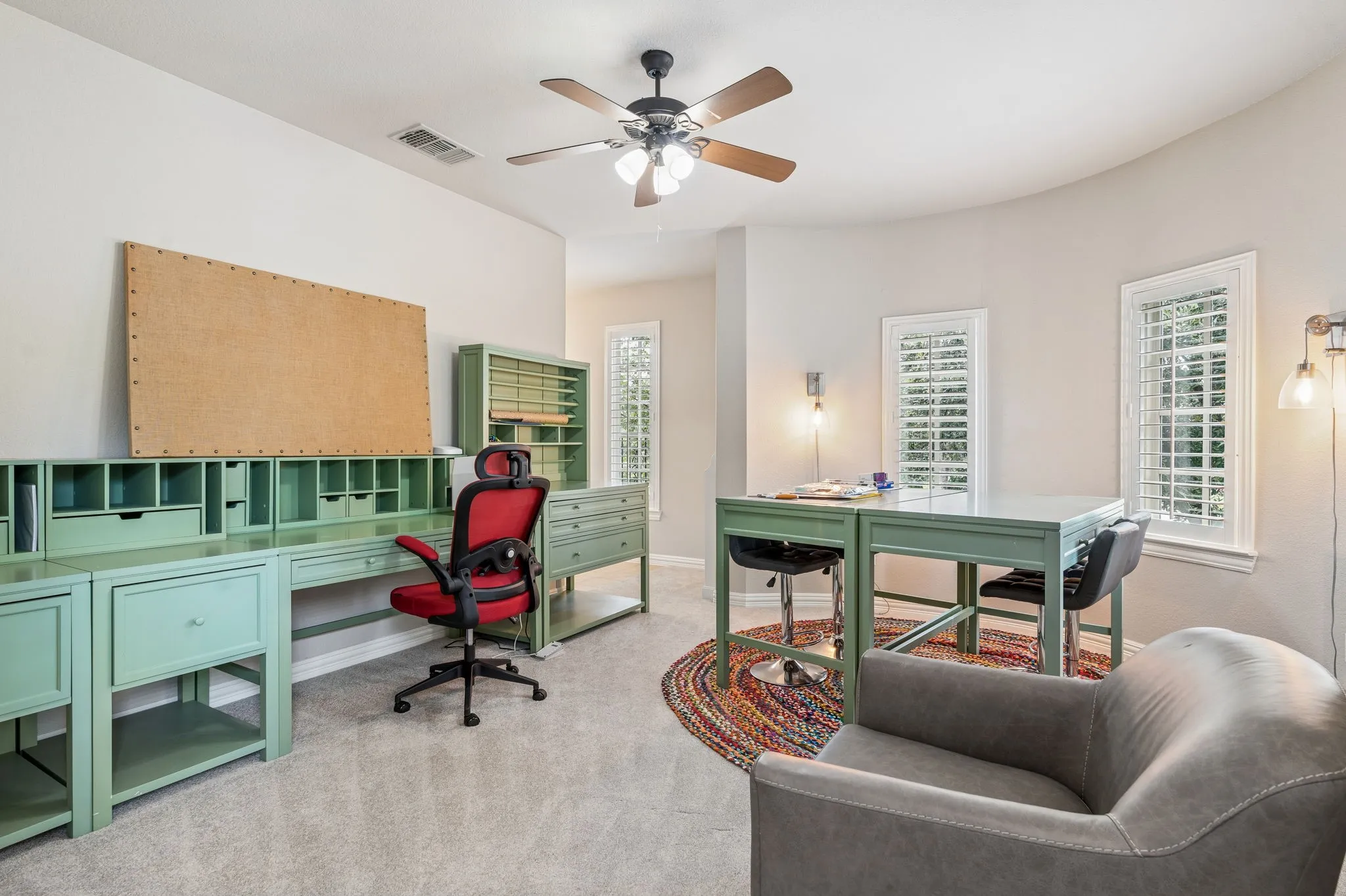 Versatile room featuring light carpeting and multiple windows with plantation shutters