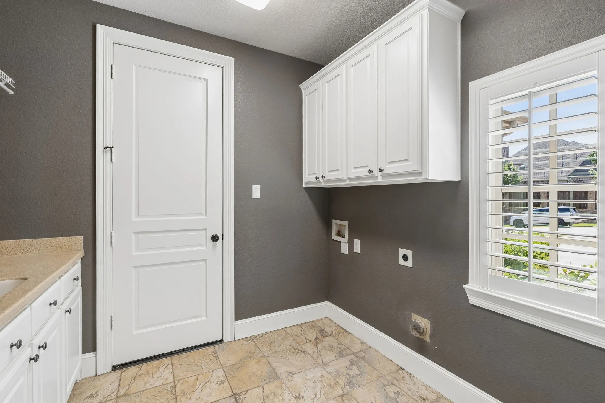 The laundry room boasts a sink and built in cabinets for storage.