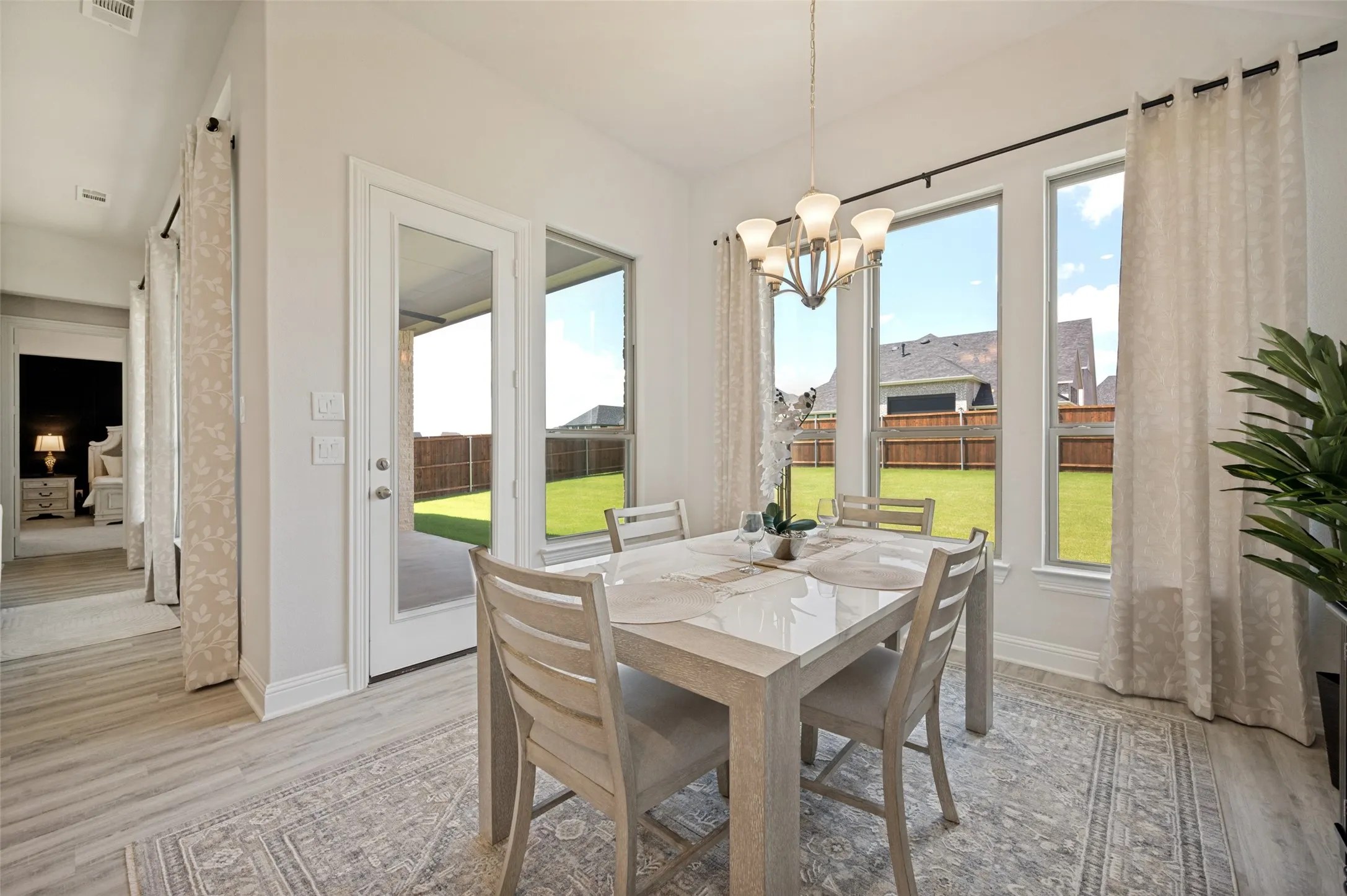 Surrounded by expansive windows and bathed in natural light, this elegant dining space offers picturesque backyard views and a seamless connection to the outdoor living area. The open layout and direct patio access create the perfect setting for intimate dinners, casual family meals, and effortless entertaining.