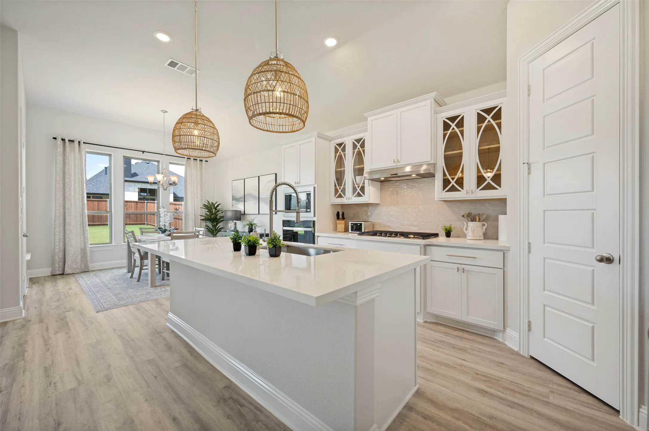 This beautifully appointed gourmet kitchen combines timeless elegance with modern functionality. Anchored by an expansive quartz island, the space features double ovens, stainless steel appliances, designer lighting, and extensive storage. The seamless connection to the dining and living areas creates an exceptional setting for entertaining and everyday living
