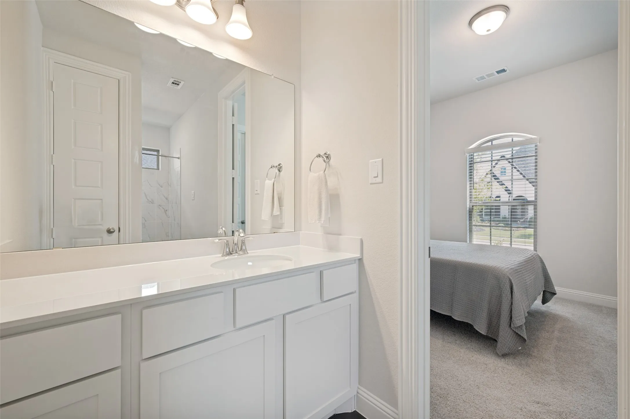 Private ensuite bath connected to the secondary bedroom, offering guests or multigenerational family members added comfort and privacy. Features a spacious vanity with quartz countertops, ample storage, and direct access to a beautifully appointed full bath with modern finishes