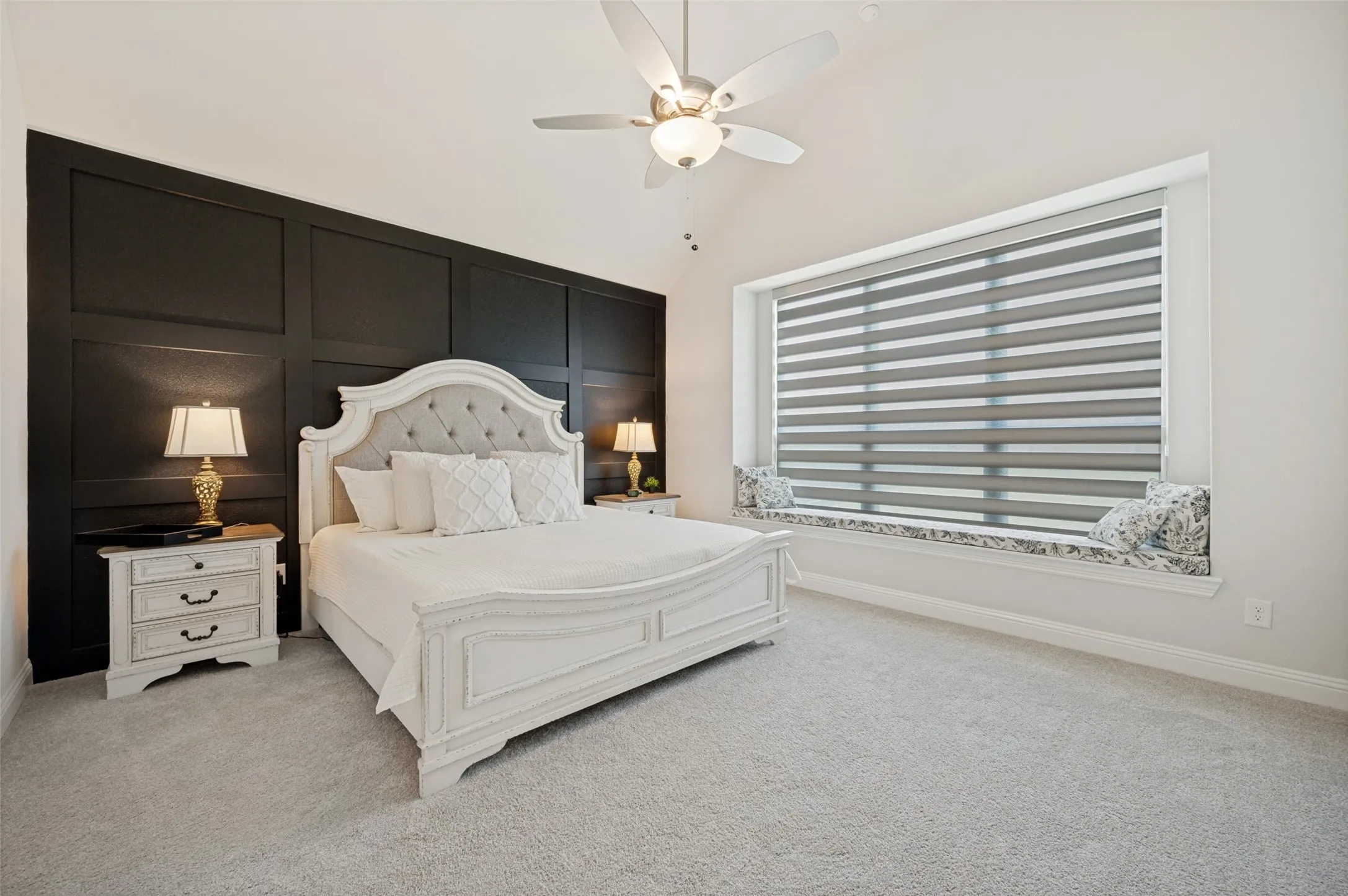 Unwind in this spacious and inviting primary bedroom featuring a designer accent wall, oversized picture window with abundant natural light, and plenty of room for a king-sized bed and additional furnishings. The neutral color palette and plush carpeting create a warm, relaxing atmosphere, while the generous layout provides the perfect private retreat to start and end your day.