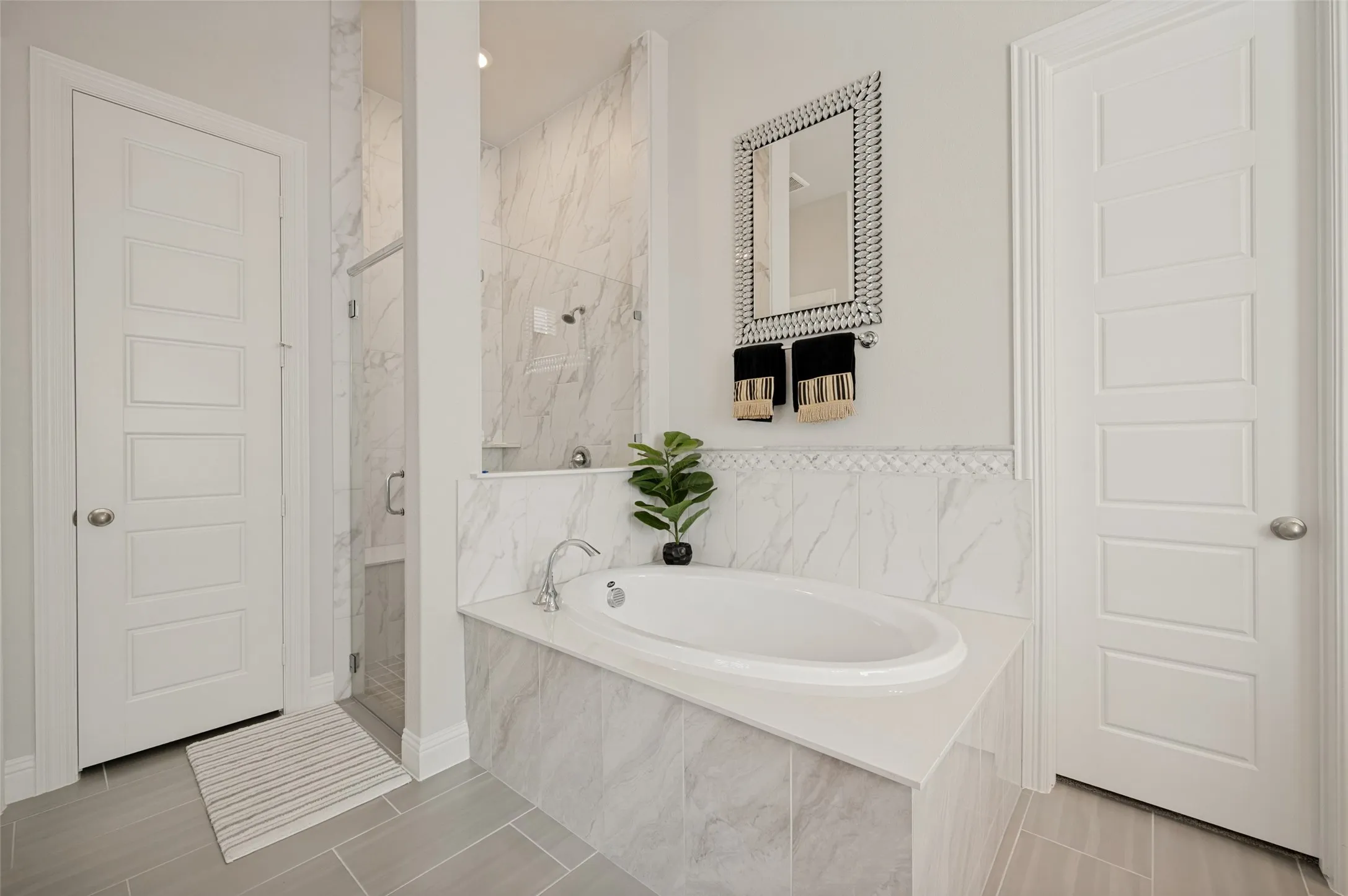 This elegant primary bathroom offers a spacious layout designed for both relaxation and convenience. Enjoy a large soaking tub framed by beautiful tile surround, the perfect place to unwind after a long day. The bright, neutral finishes, decorative niche, and thoughtful design create a spa-like atmosphere, while the adjacent dual-vanity area and generous storage make everyday living effortless.