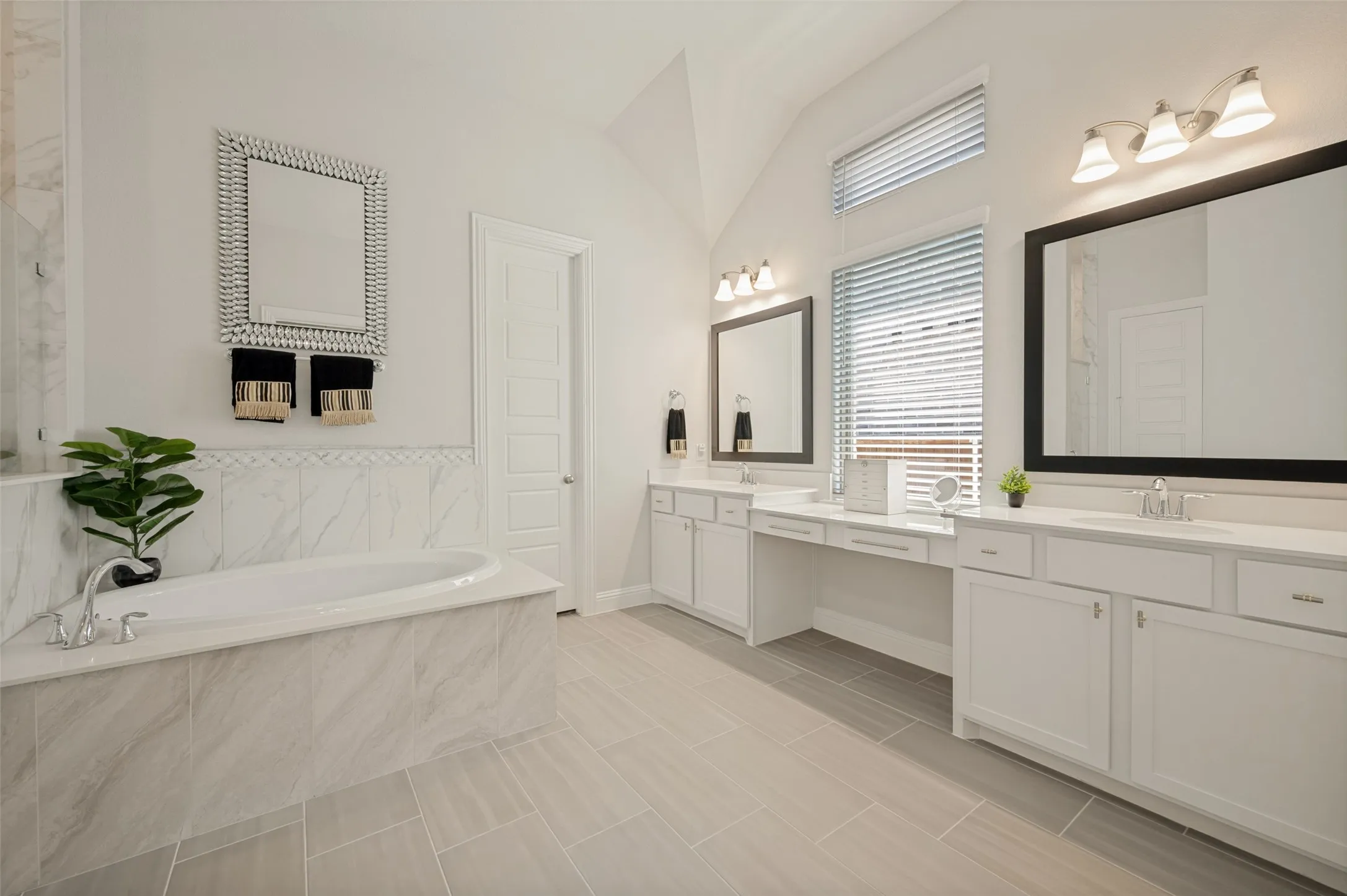 ndulge in this spacious primary bathroom designed with both comfort and functionality in mind. Featuring an expansive dual-sink vanity, abundant cabinet storage, and oversized framed mirrors, this elegant space offers plenty of room for busy mornings. The bright, neutral finishes and open layout create a spa-like atmosphere, while the large soaking tub provides the perfect place to relax and unwind after a long day.