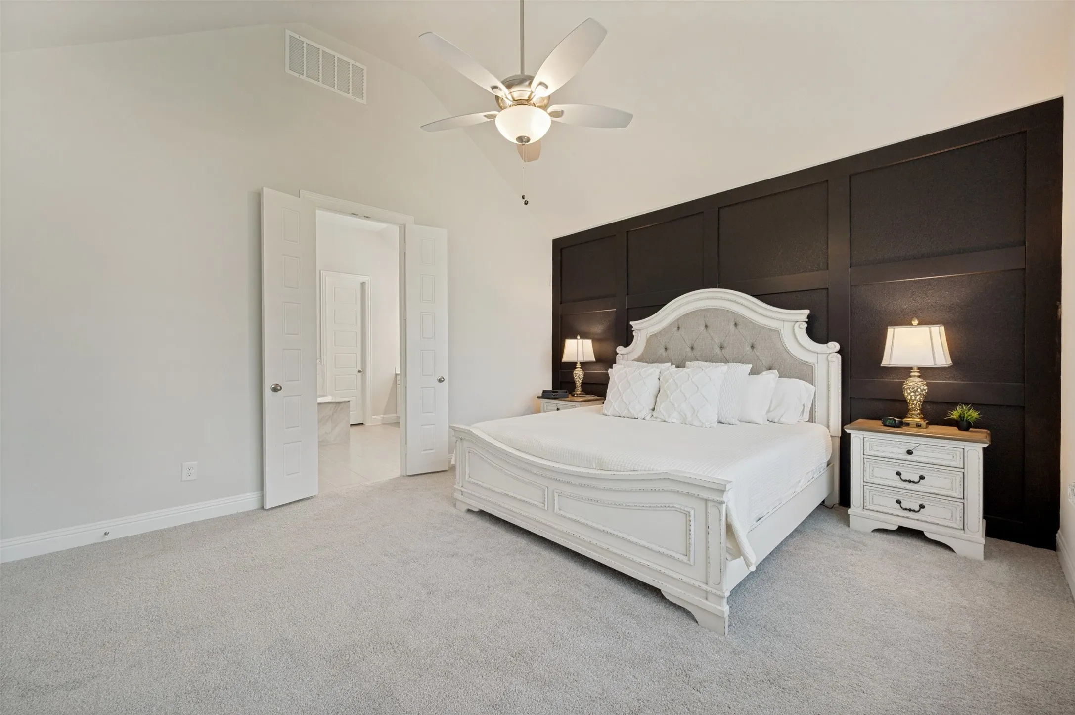 Retreat to the spacious primary suite featuring plush carpeting, abundant natural light, and a striking accent wall that adds warmth and character. The room easily accommodates large furniture while maintaining an open and airy feel, creating the perfect space to relax and unwind at the end of the day. Elegant finishes and a soothing color palette make this owner's retreat both comfortable and inviting.
