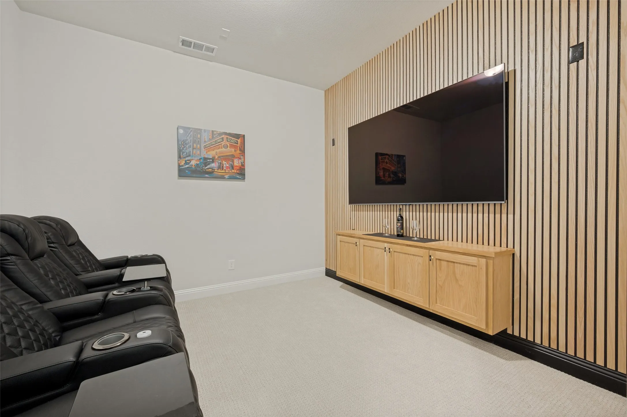 Dedicated media room featuring a striking wood accent wall, custom built-in cabinetry, and ample space for theater seating. The perfect setting for movie nights, game days, or streaming your favorite shows in style and comfort.