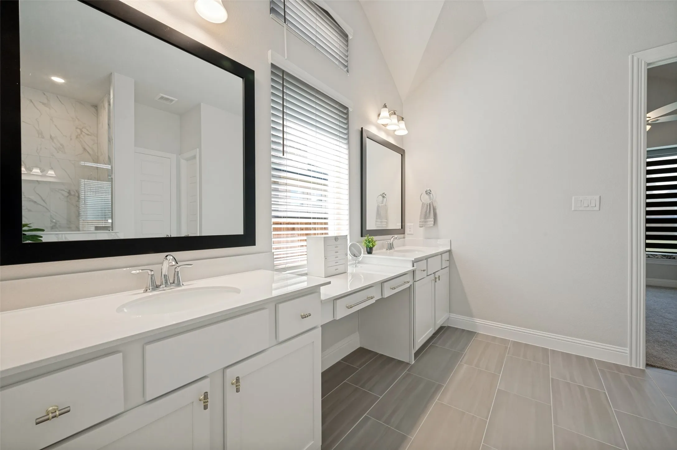 Enjoy a spa-like experience in this beautifully appointed primary bathroom featuring an extended dual-sink vanity with abundant counter space, elegant framed mirrors, and ample storage. The bright, neutral finishes create a clean and timeless look, while the spacious layout offers both comfort and functionality for everyday living. Thoughtfully designed for convenience, this luxurious bath provides the perfect complement to the private owner's retreat.