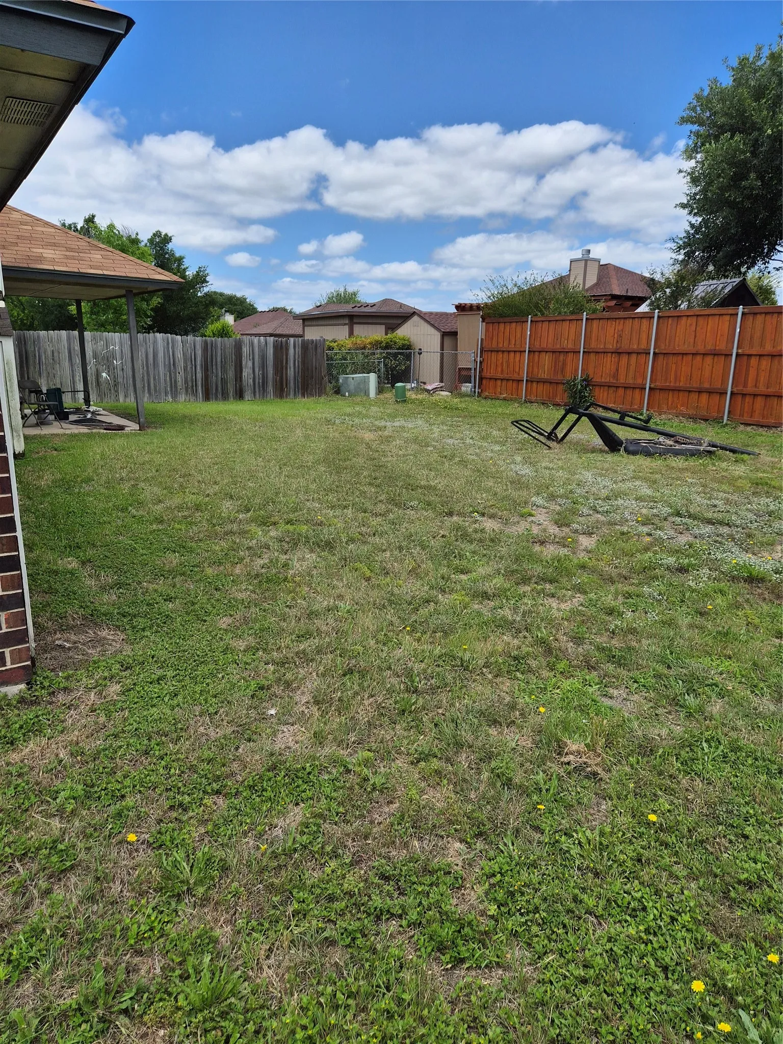 Expansive backyard with a covered patio, brick exterior, and a combination of wood and stained privacy fencing