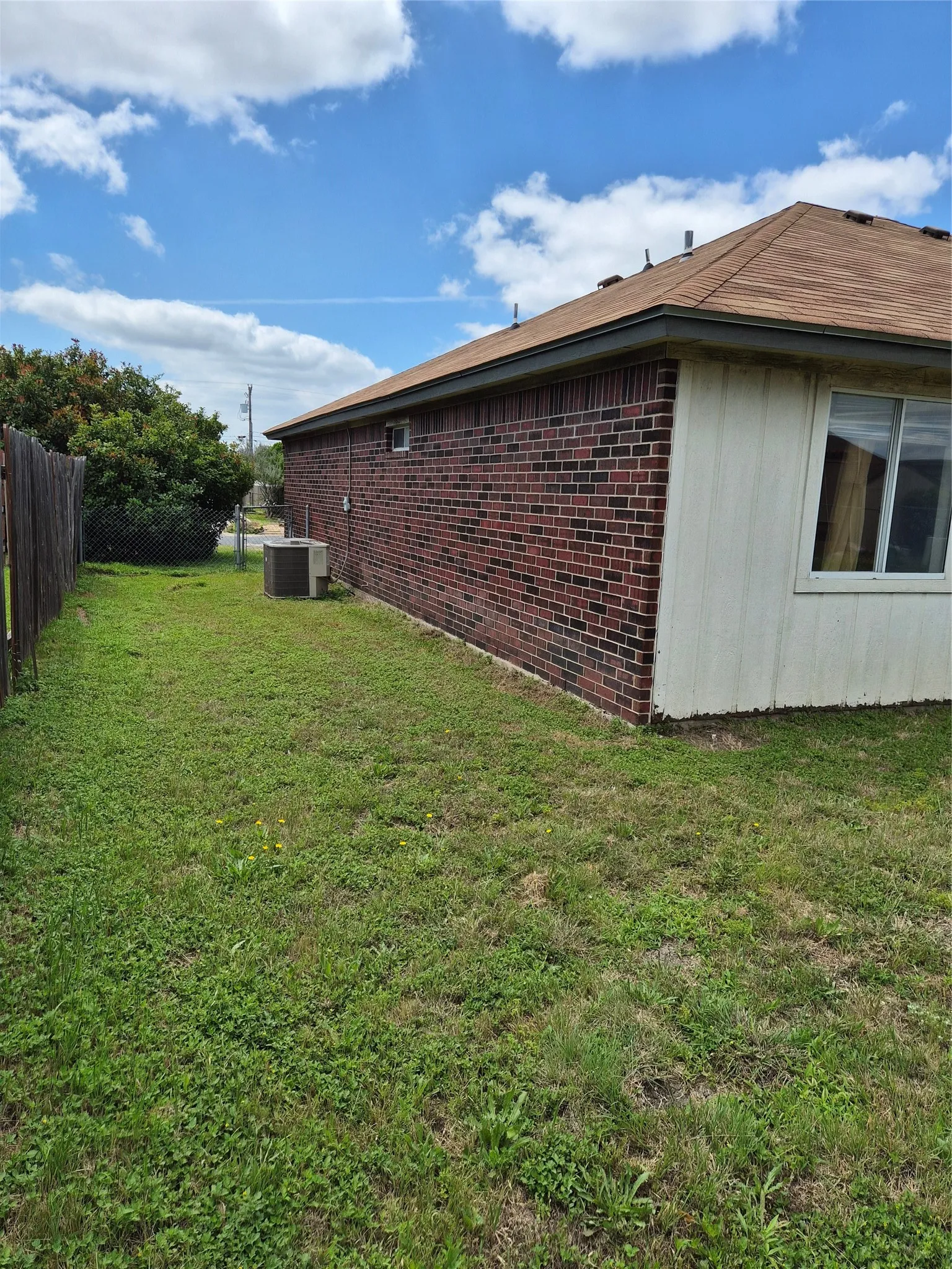 Brick exterior with a brown shingle roof and white siding