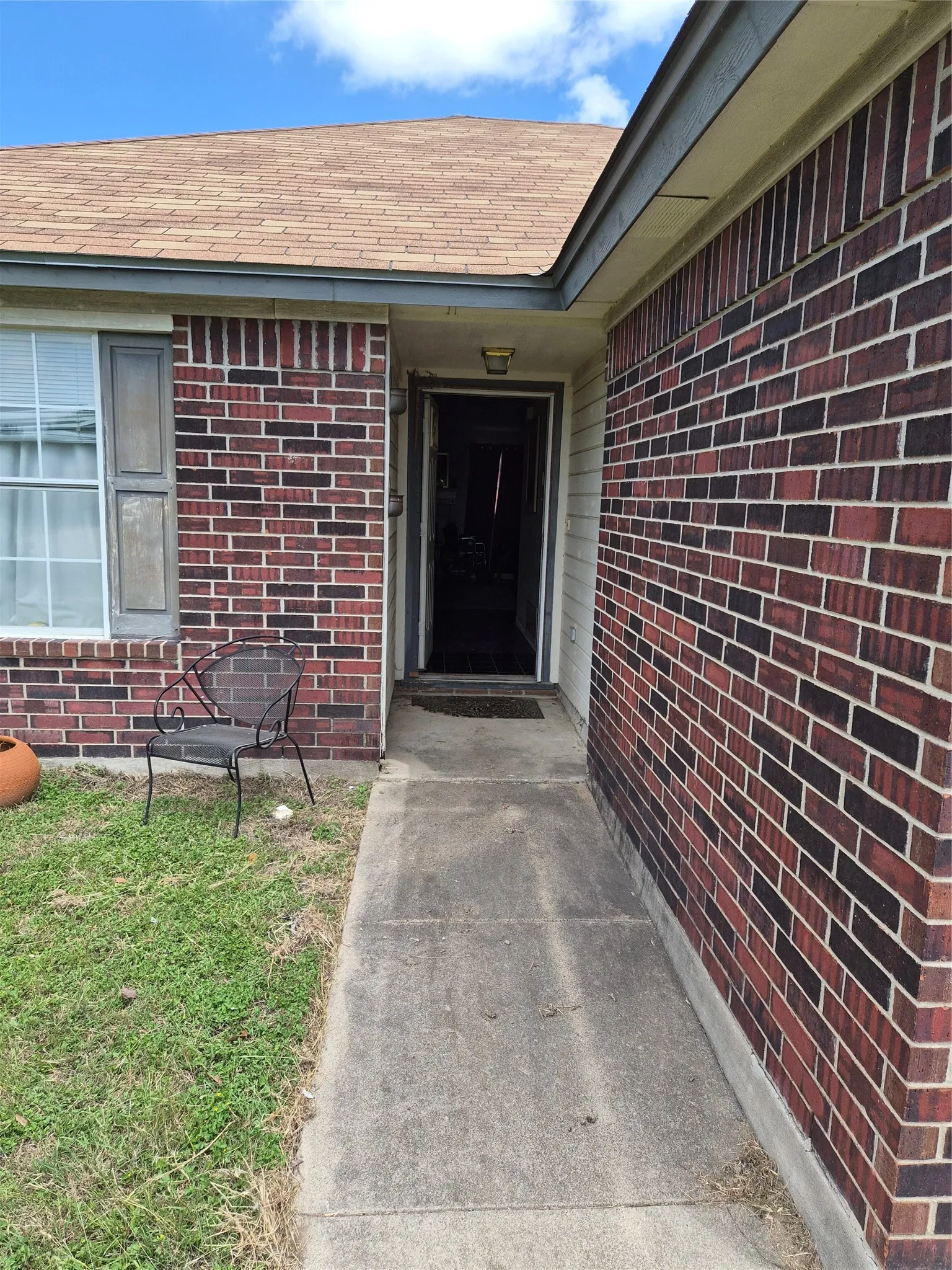 Brick exterior with a gabled roof featuring architectural shingles