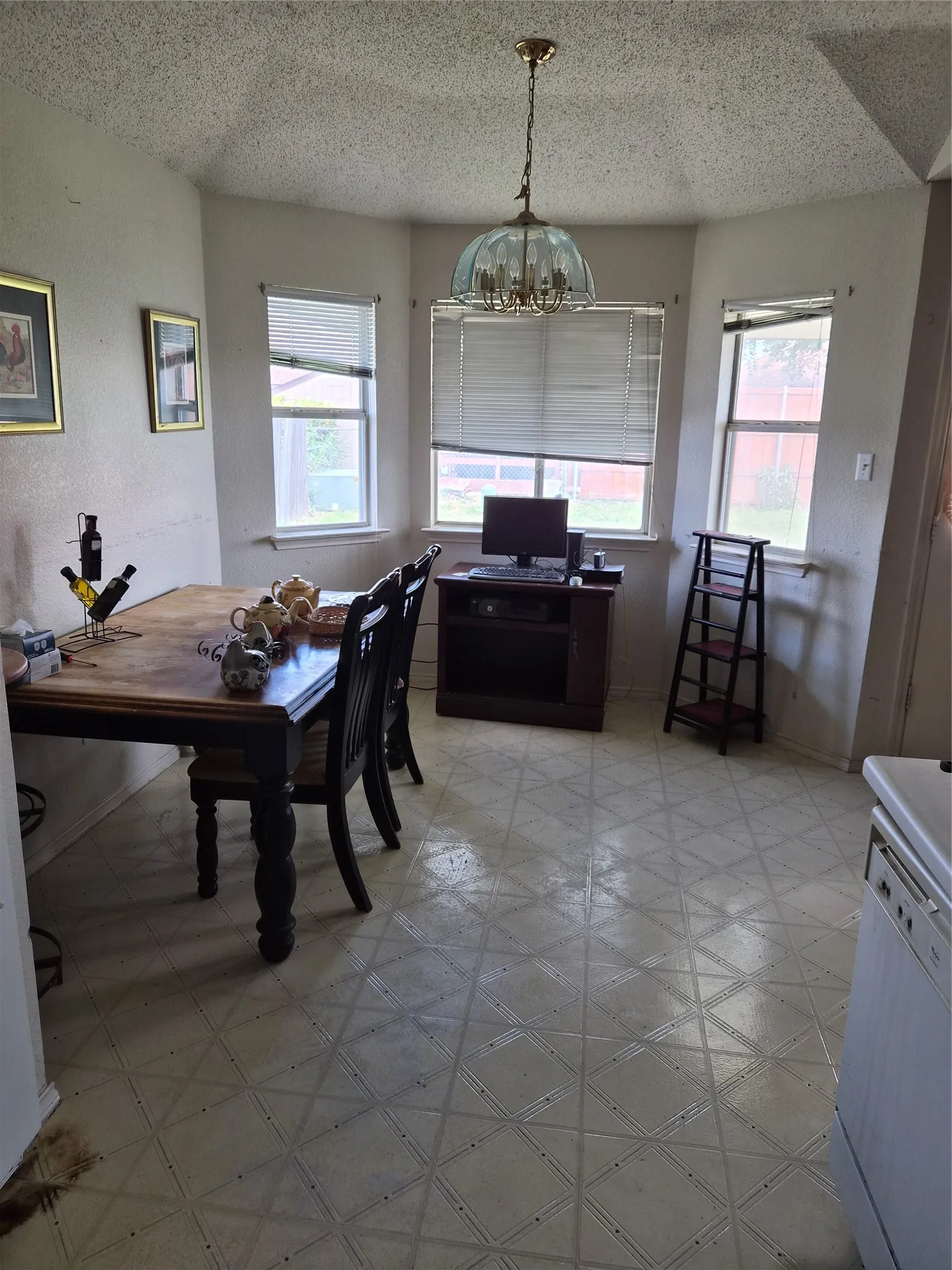 Bay window area featuring patterned flooring, multiple windows with blinds, and a ceiling-mounted light fixture