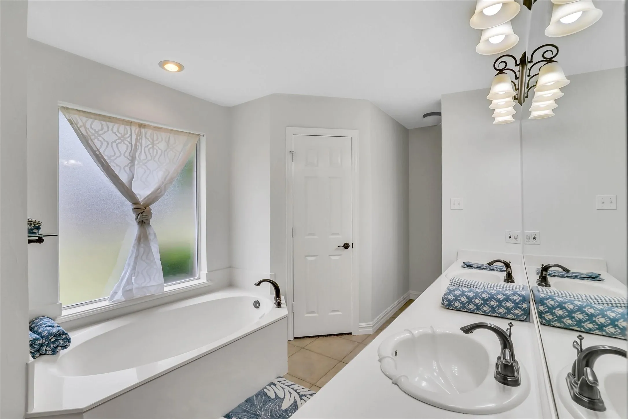 White soaking tub with dark bronze fixtures, set against a frosted window