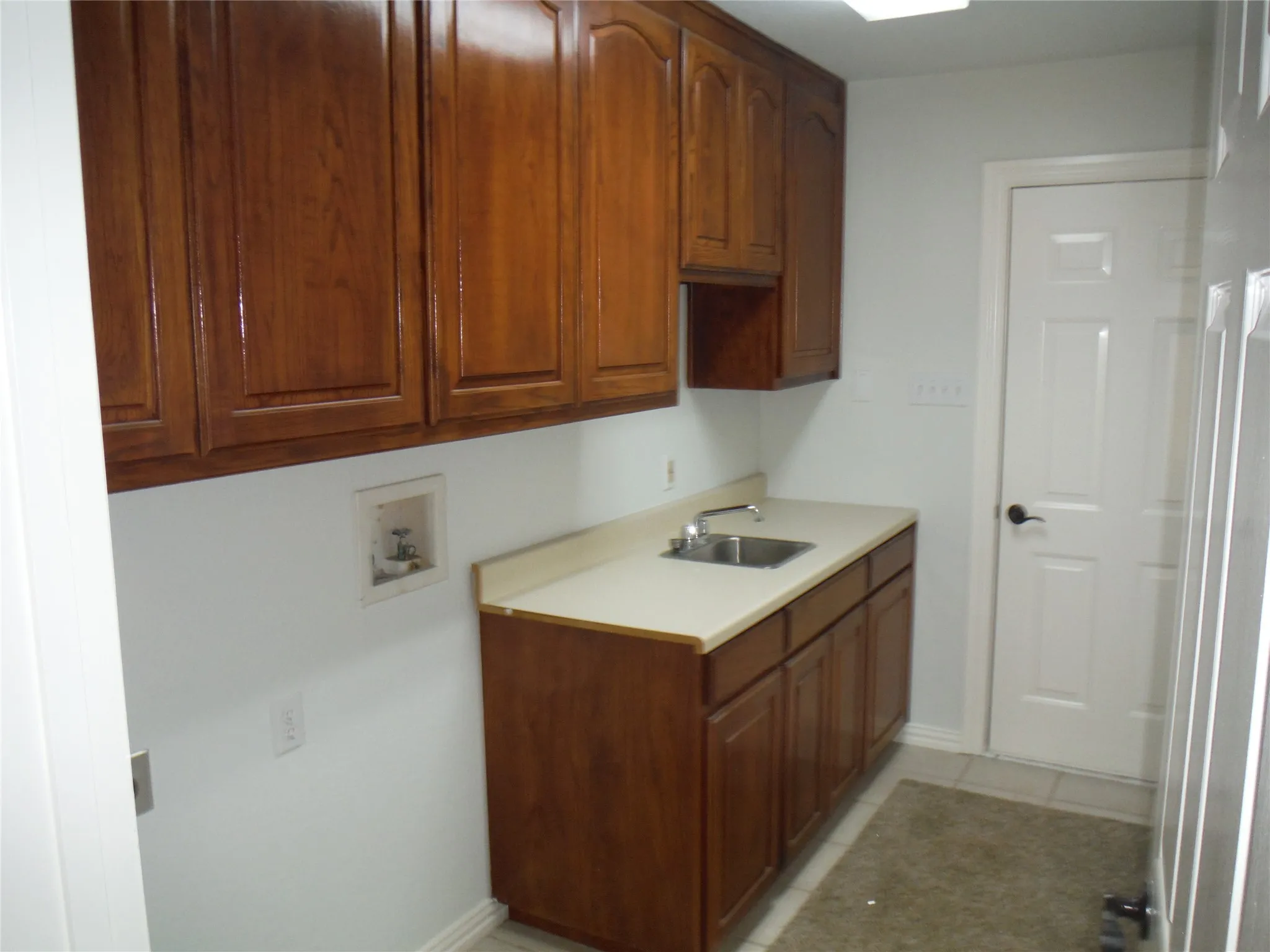 Nice utility room loaded with cabinets and a sink.
