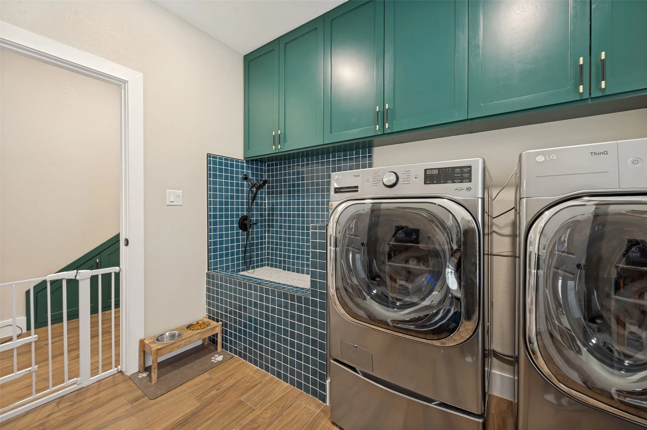 This thoughtfully designed utility room combines everyday functionality with pet-friendly convenience. The stylish blue tile of the elevated dog-wash station adds a pop of color and character while creating a practical space for pet care. Whether handling laundry, storage, or caring for four-legged family members, this versatile utility room is designed to simplify daily living. Cabinetry above has been added to this space for all your storage needs.