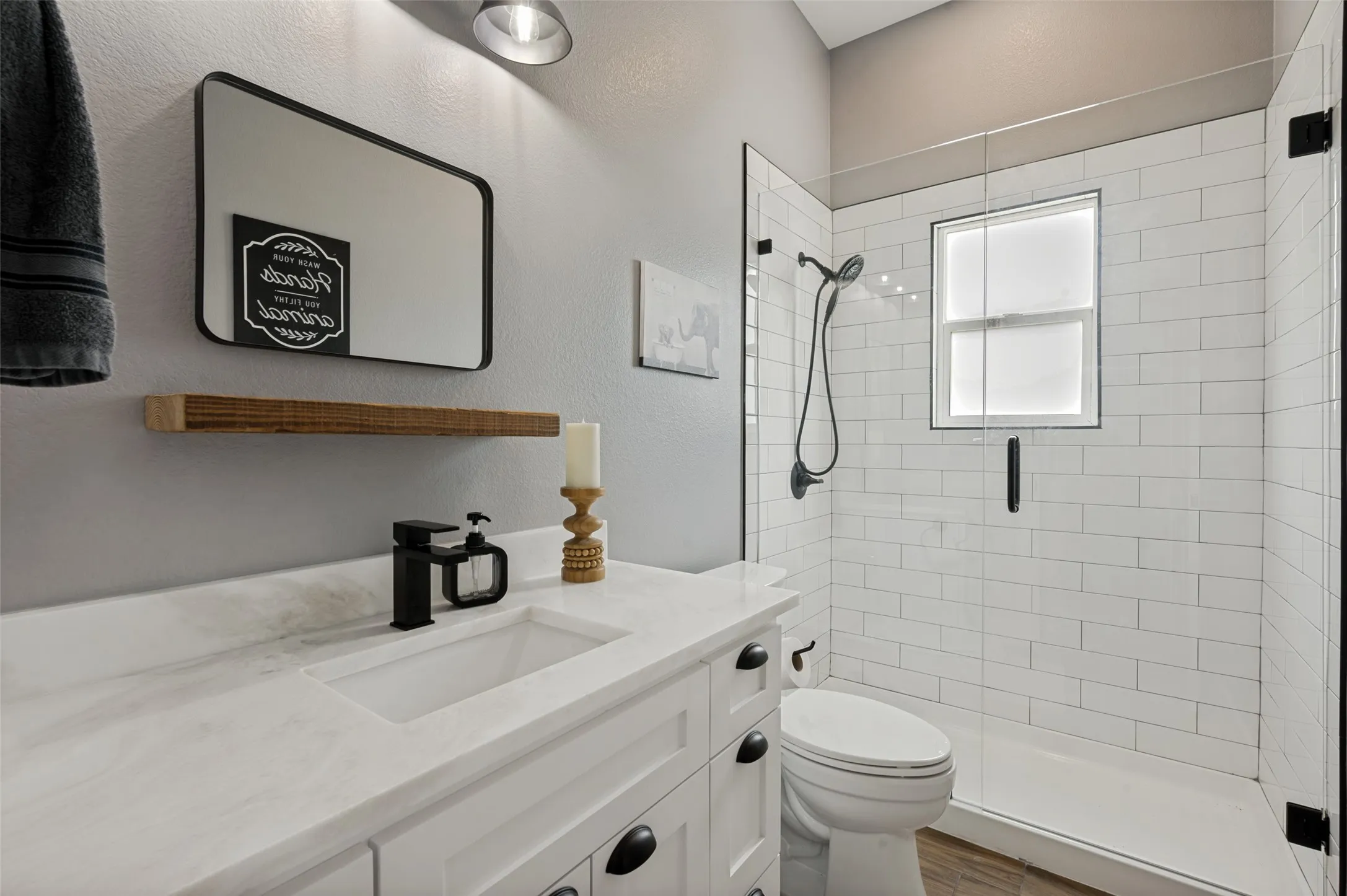 Conveniently located adjacent to the bonus room, this beautifully appointed full bathroom offers both style and functionality for guests and family alike. The bright, modern design features a sleek quartz-topped vanity with crisp white cabinetry, contemporary black fixtures, and clean-lined finishes throughout. A spacious walk-in shower showcases timeless subway tile, a frameless glass enclosure, and a window that fills the space with natural light while maintaining privacy. Neutral tones and designer details create a fresh, inviting atmosphere, making this full bath the perfect complement to the upstairs living and entertainment space.