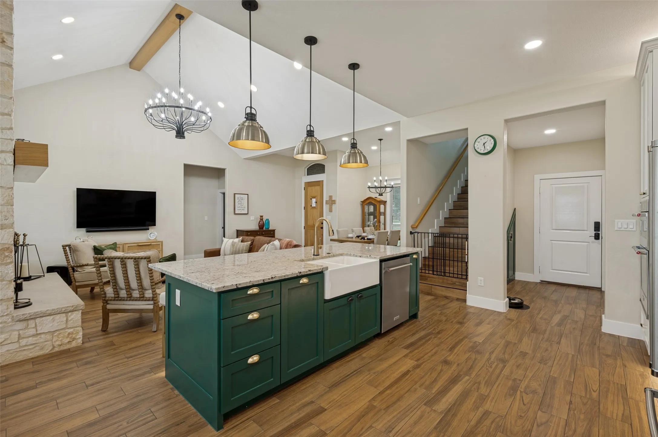 Designed to impress and built for everyday living, this stunning kitchen serves as the heart of the home. The spacious open-concept layout features an oversized island with striking deep green cabinetry, elegant granite countertops, and an apron front farmhouse sink, providing ample space for meal preparation, casual dining, and entertaining. Notice the stairwell to the bonus room on the right. Mudroom to the right has cabinets built-in to the wall for additional storage. Garage door enters conveniently into the kitchen--a nice feature when you are coming home from the grocery store.