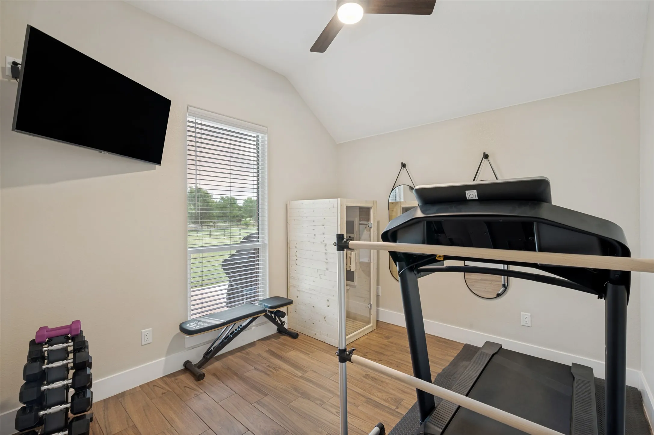 This versatile secondary bedroom offers the perfect blend of comfort and flexibility. Featuring vaulted ceilings, warm wood-look flooring, and abundant natural light, the space feels bright, open, and inviting. Large windows provide peaceful views of the surrounding property, creating a relaxing atmosphere. With generous dimensions and a functional layout, this room easily accommodates a bedroom, home office, fitness space, or hobby room. The closet in this bedroom is to the left, just outside of the camera's view in this photo.