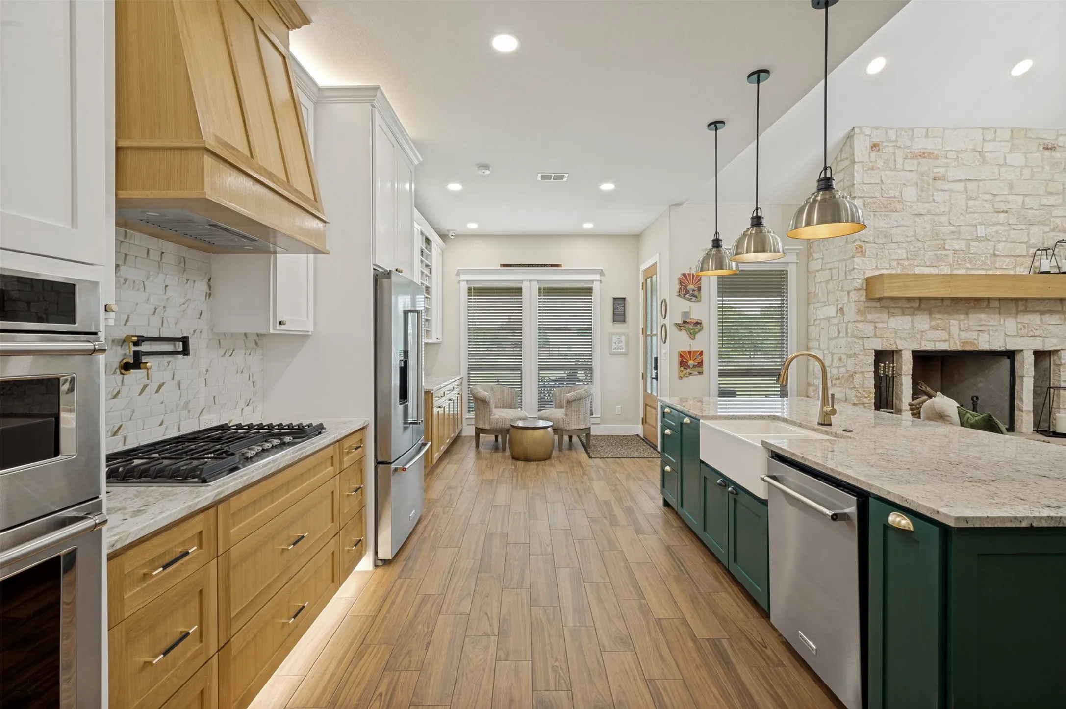 Open sightlines to the living and dining areas, soaring ceilings, and warm wood-look flooring enhance the home's airy feel, making this kitchen the perfect gathering place for family and friends. Cooks will love the convience of the pot filler over the 5 burner gas cooktop. To your left is the built in microwave and built in oven. Notice the stainless steel appliances and matching pendant lights.  Straight ahead is the breakfast nook overlooking the lovely backyard.