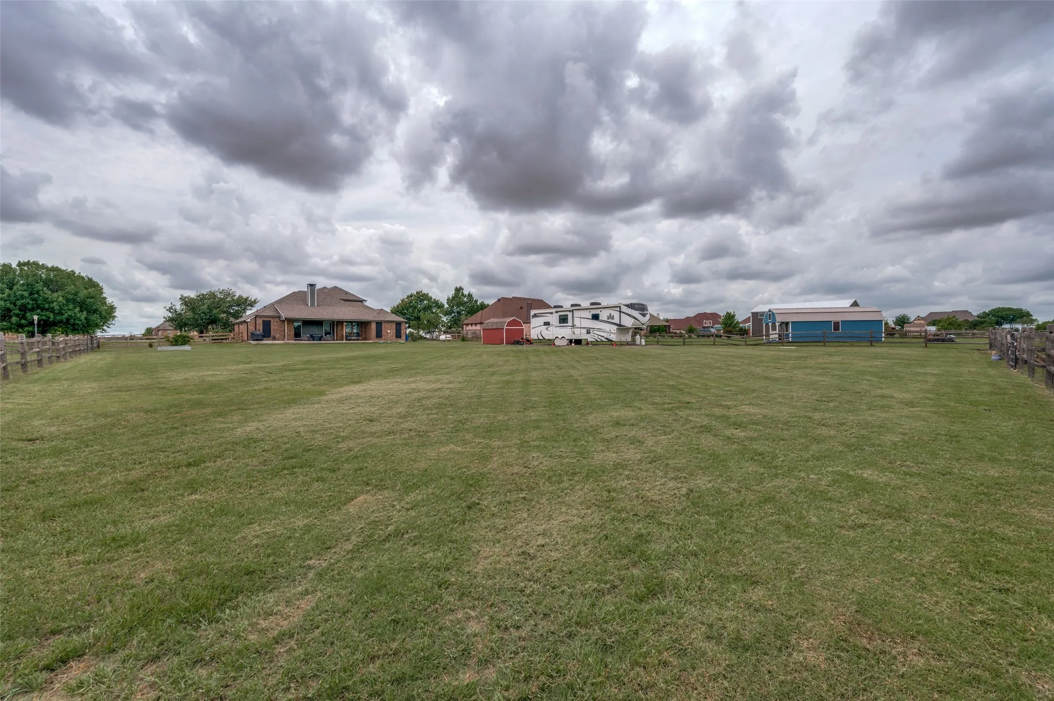 The sprawling green space creates a sense of openness and freedom rarely found, while the ranch-style fencing defines the property boundaries and enhances its charming rural character. A barn-style storage building provides convenient space for equipment, tools, and outdoor essentials, and there is ample room for RV, boat, or trailer parking. Surrounded by wide-open skies and picturesque views, this remarkable property offers the perfect balance of modern comfort and country appeal, with plenty of room to spread out, relax, and enjoy the outdoors.