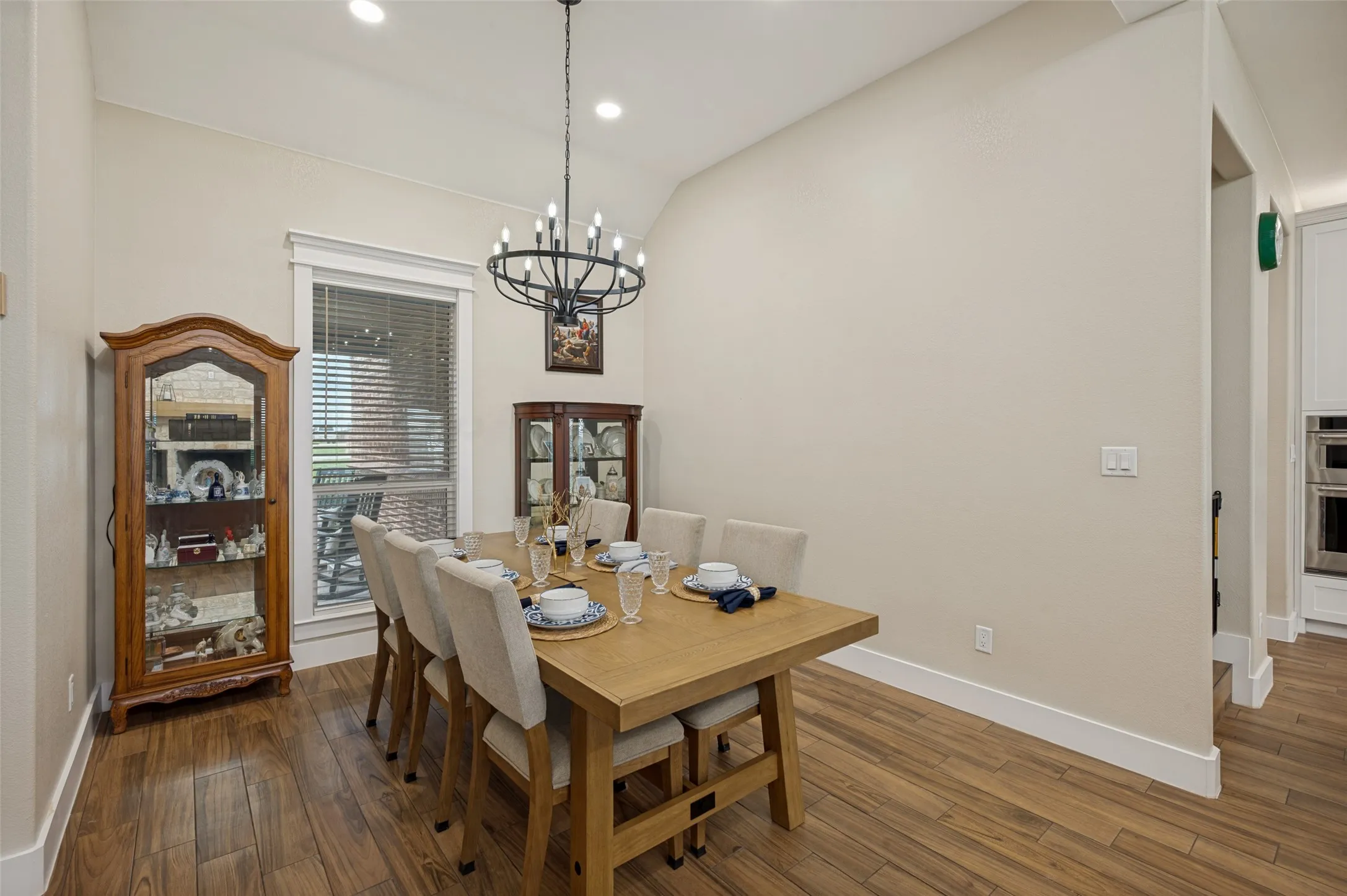 The formal dining area offers the perfect blend of elegance and functionality, ideally positioned to take advantage of the home's open-concept design. Notice the chandelier that matches the main living area chandelier. Notice the tall baseboards, additional recessed lighting, and lovely view of the front yard from the oversized window.