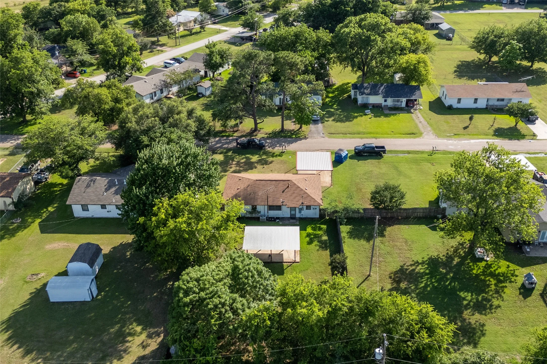 Aerial view of a residential property featuring a central single-story home with a brown shingle roof