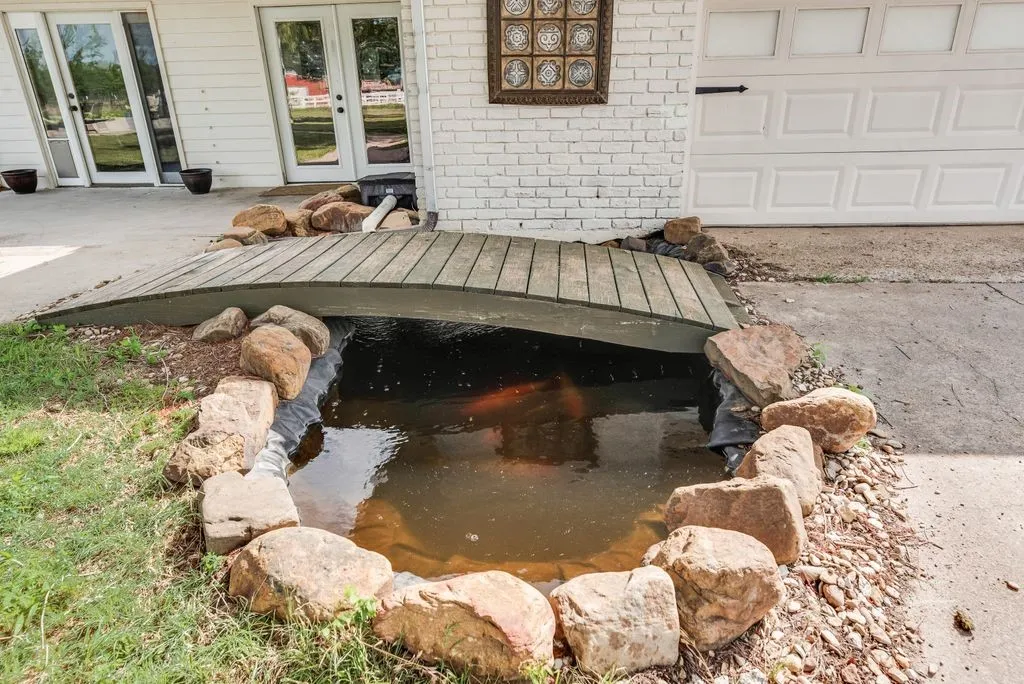 Decorative koi pond featuring a wood bridge accent and natural rock surround