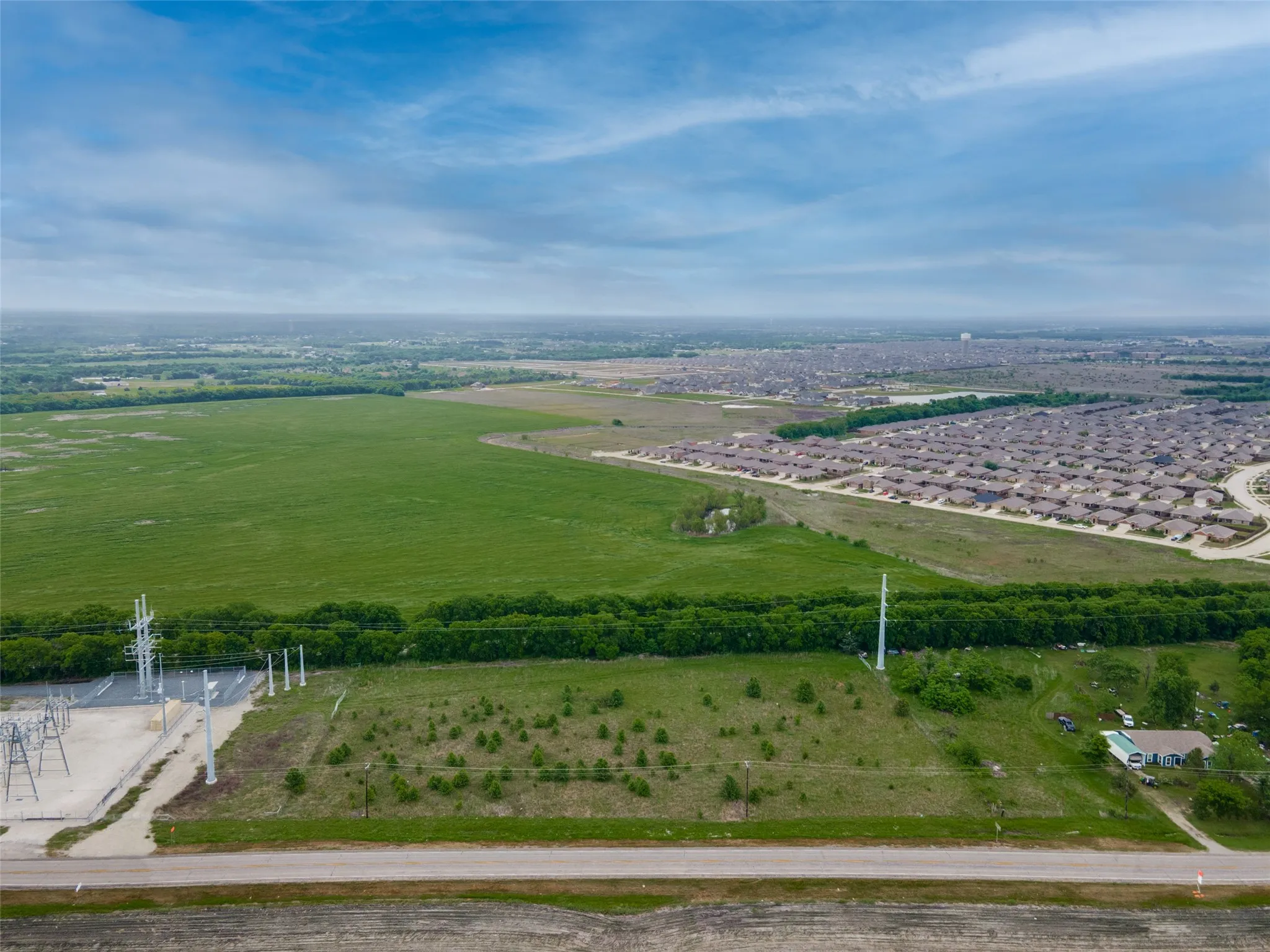 Expansive green fields with a visible road running through the foreground