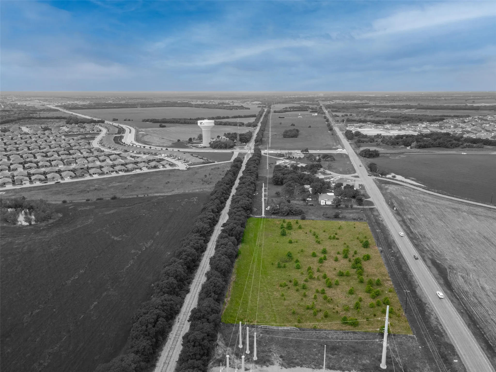 Expansive green lot with established trees, bordering a paved road