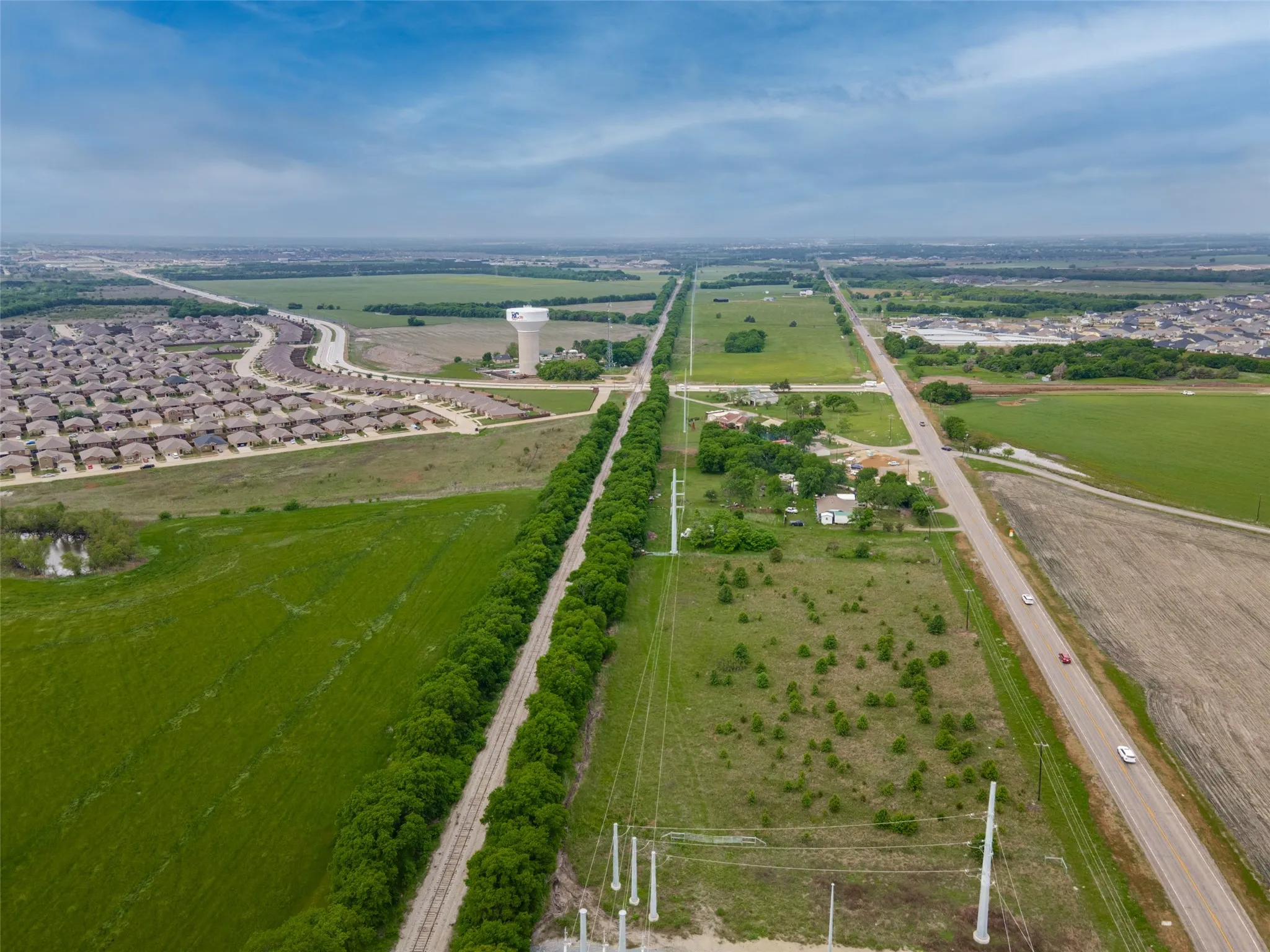 Expansive aerial view showcasing multiple residential developments, green fields, and roadways